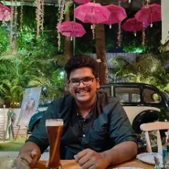 Minimalist profile shot of a man with long braids and a white shirt, set against a soft, light background.