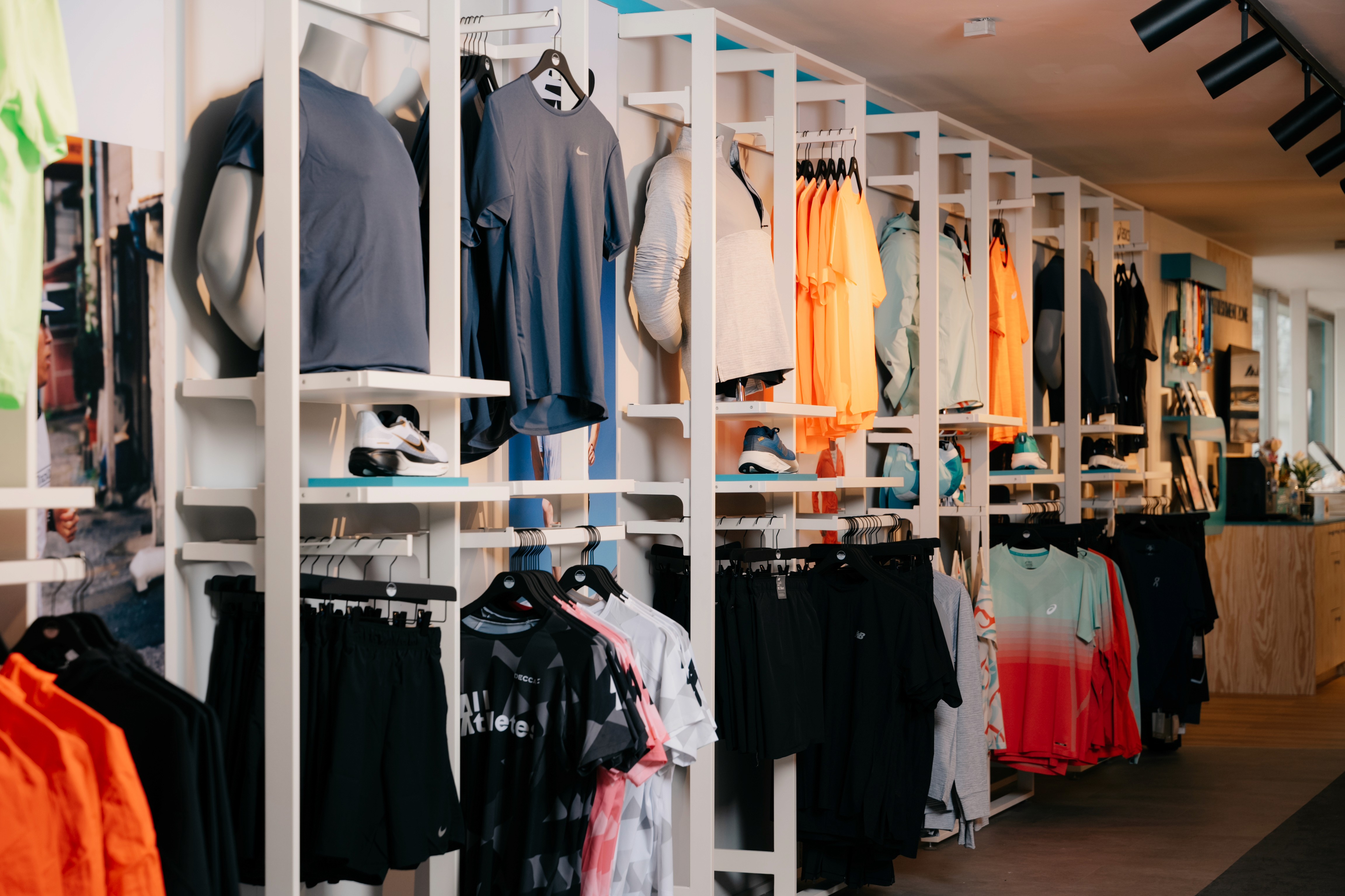 Modern red brick apartment or office building viewed from below against a blue sky, showcasing its geometric architecture with evenly spaced windows and balconies.
