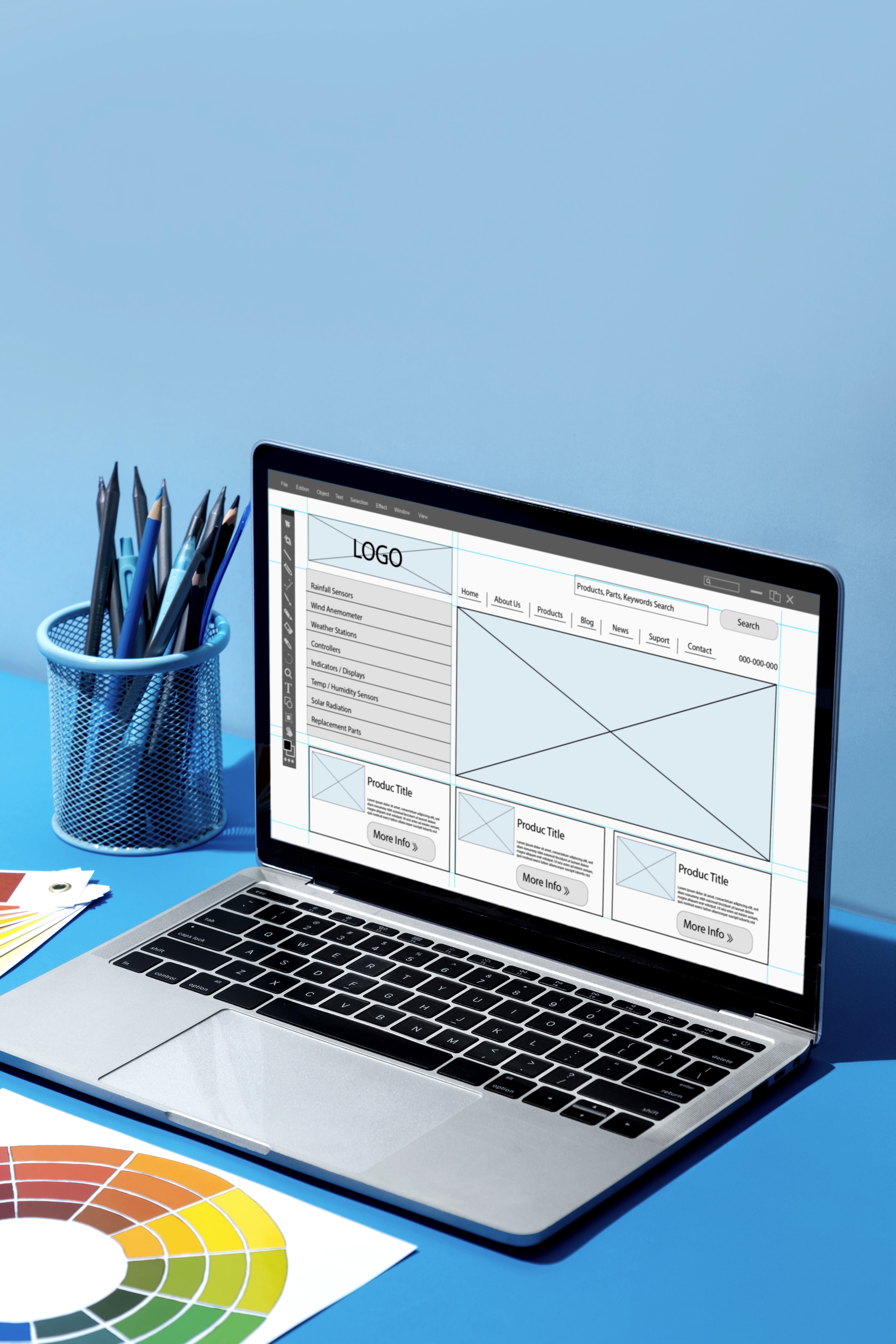 Laptop displaying a website wireframe and layout structure on a desk with design tools and colour swatches.
