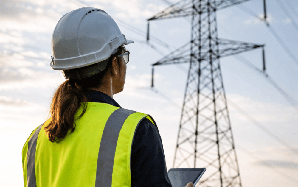 Ingenjör som står utomhus vid en kraftledning