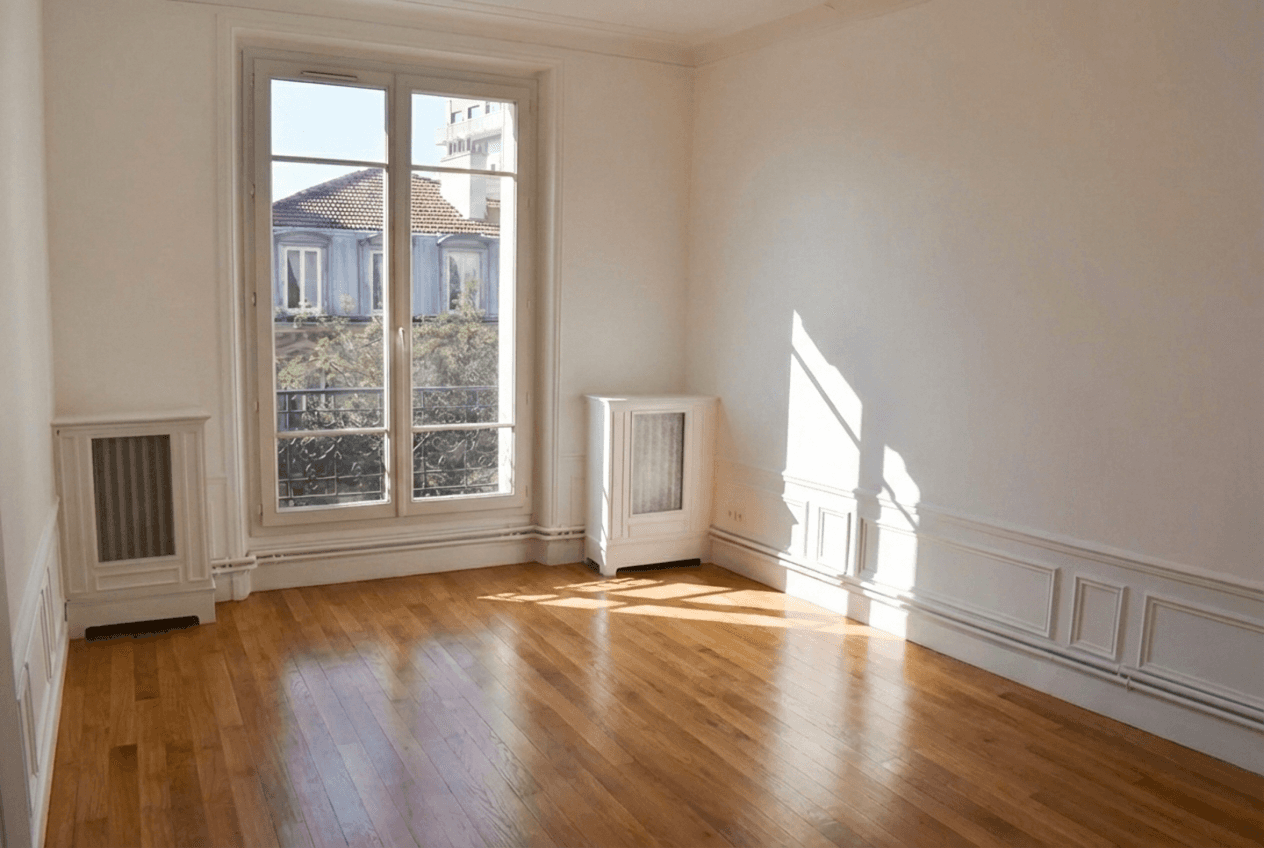 Pièce de vie baignée de lumière naturelle mettant en valeur la restauration du sol en bois et les détails architecturaux.