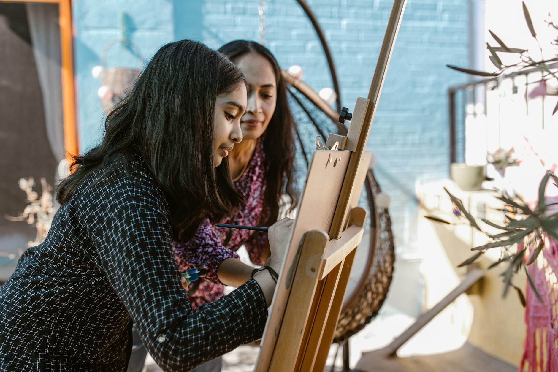 A young girl happily painting a colorful landscape on a canvas to express her creative learning style.