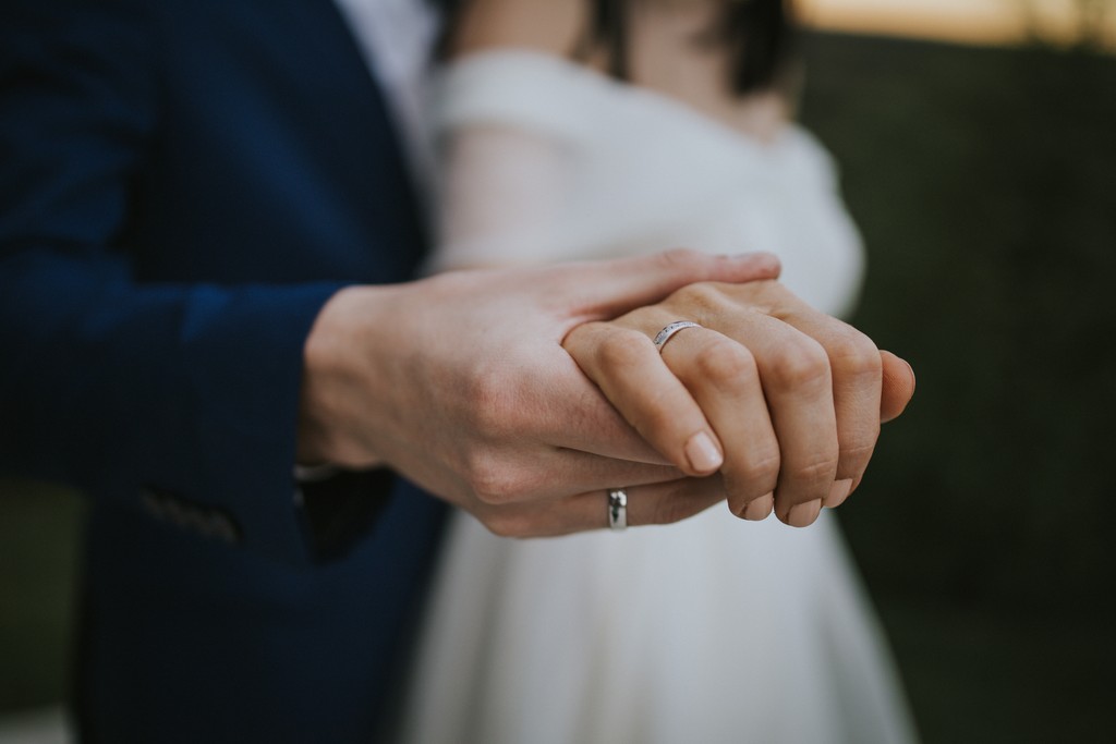 Bride and groom holding hands showing wedding rings
