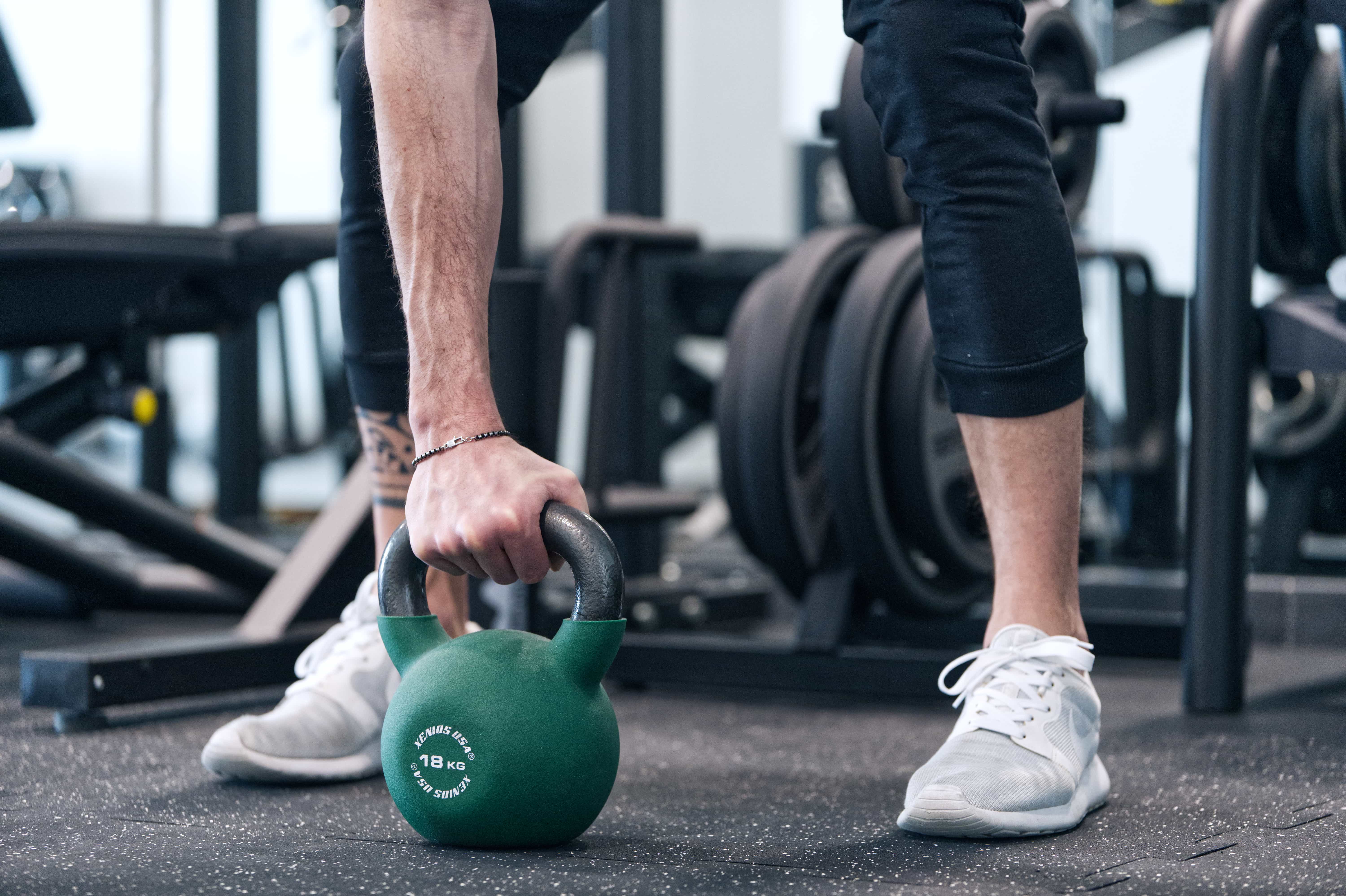 A man in a brown blazer and a woman in a light sweater sit at a desk with a laptop, discussing something. The room is dimly lit, creating a focused atmosphere.
