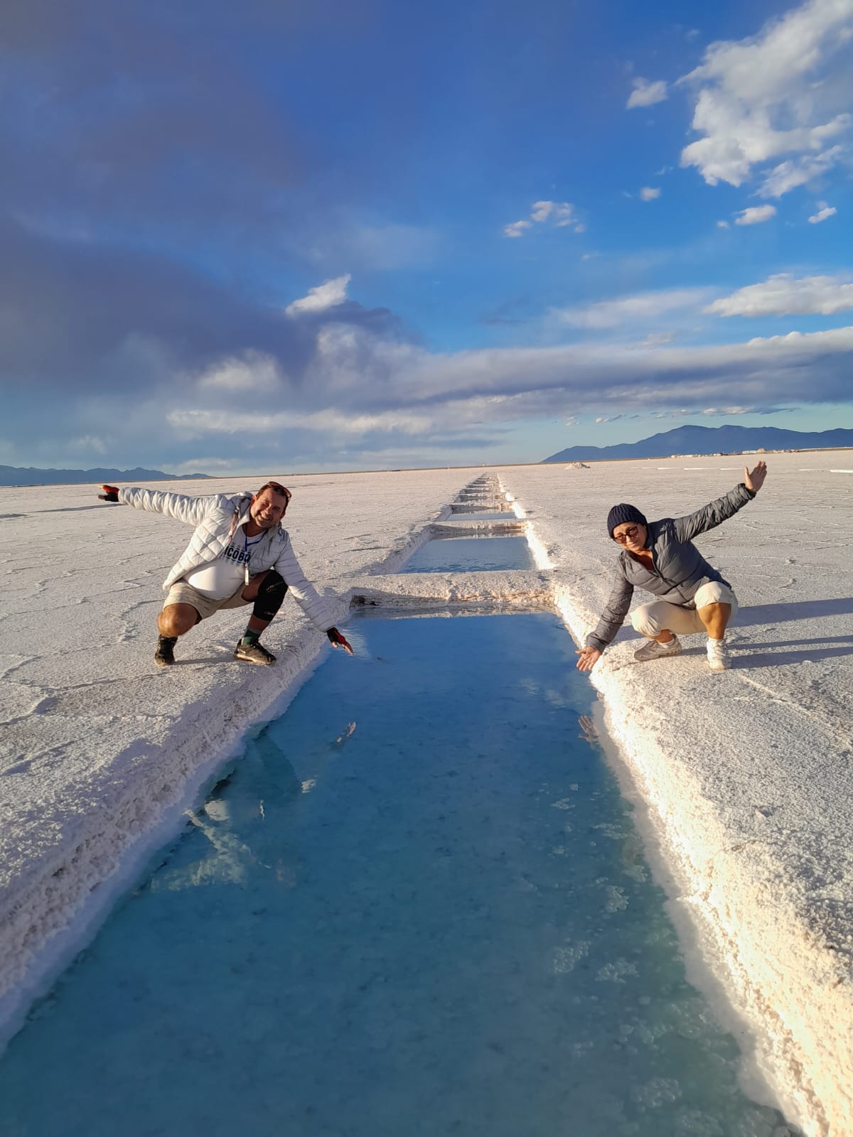 Mujer sentada sobre un tronco frente a una cascada doble en un bosque frondoso de Argentina.