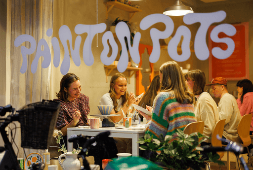 Mennesker som koser seg med å male på keramikk inne i et lokale