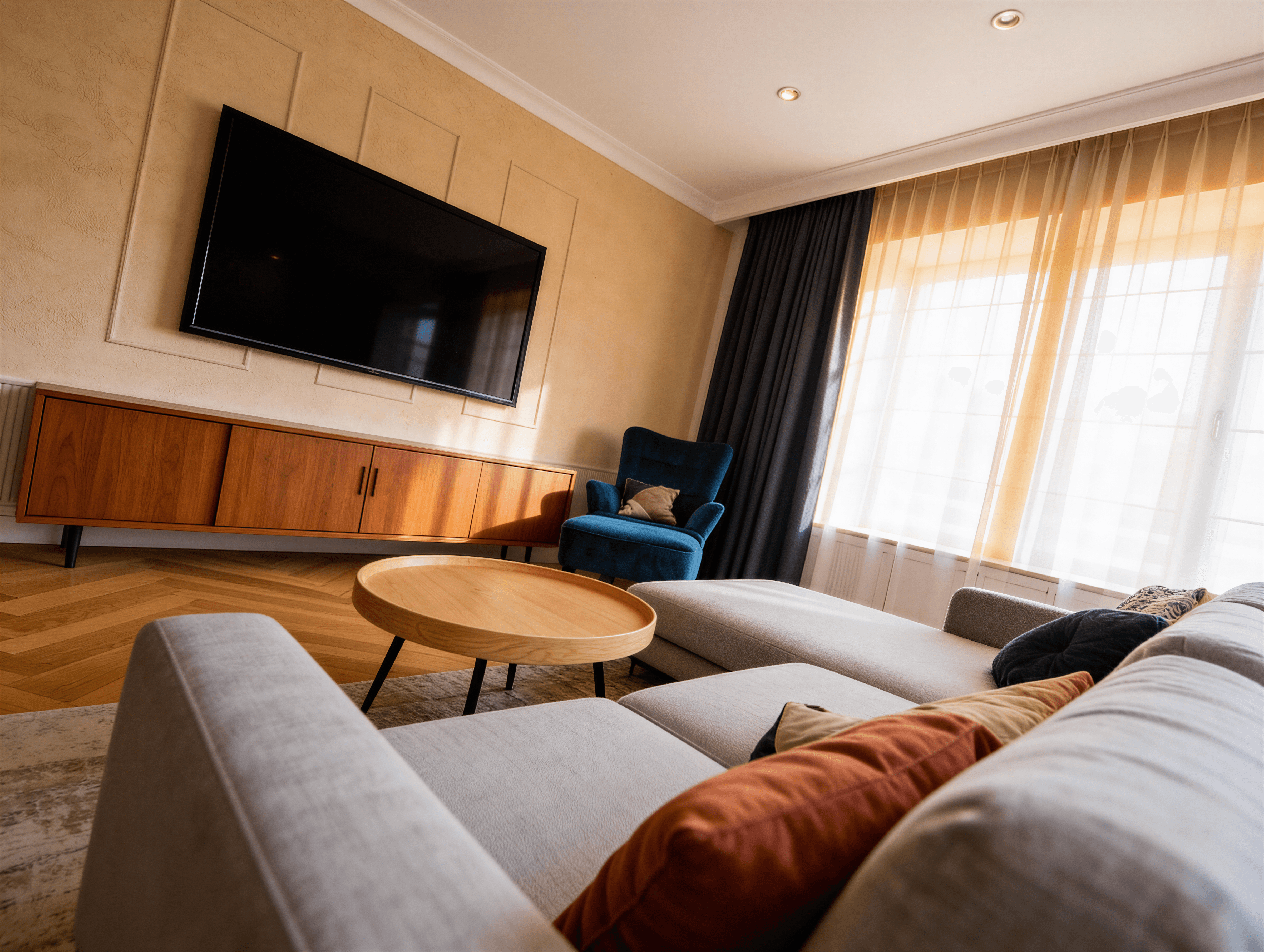 Living modern cu perete media placat cu lemn, TV suspendat, canapea gri și accente portocalii.