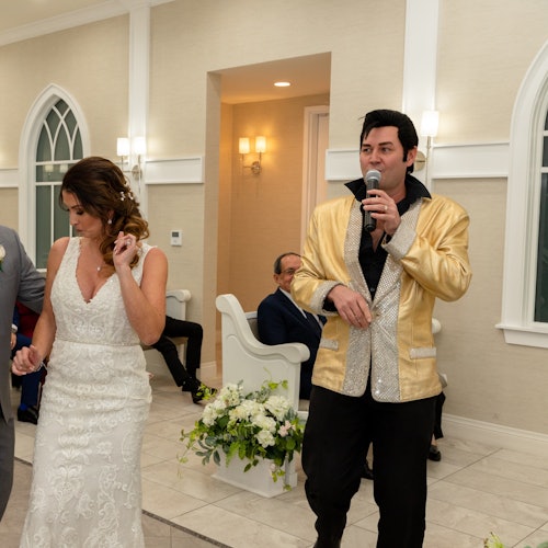 一位穿金色夹克的人正在对着麦克风唱歌,而旁边一位穿白色连衣裙的女士正在跳舞。