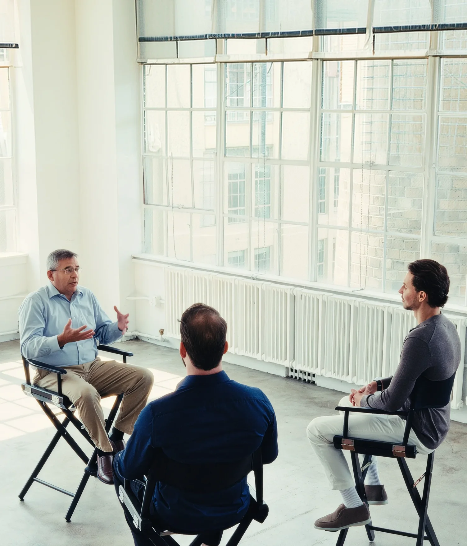 Three people seated in director chairs for an interview in a bright loft