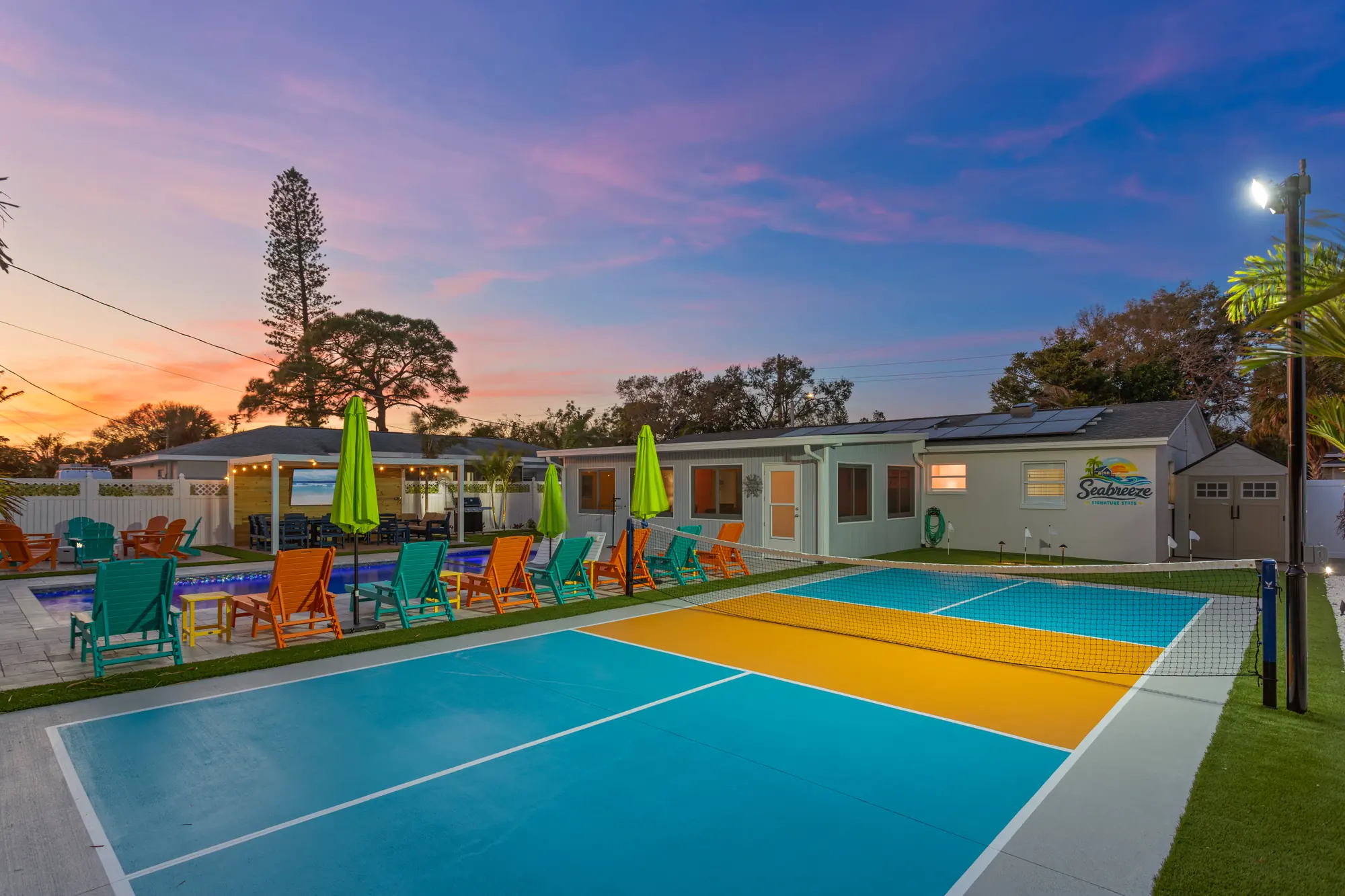 Private pickleball court at sunset with colorful Adirondack chairs and lime umbrellas by the pool at Pickleball Resort, Bradenton, Florida