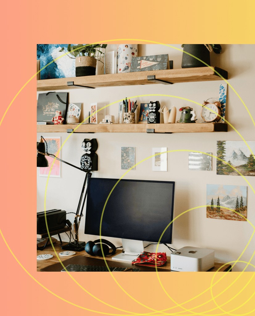 Desk with computer, shelves, and artwork on wall.