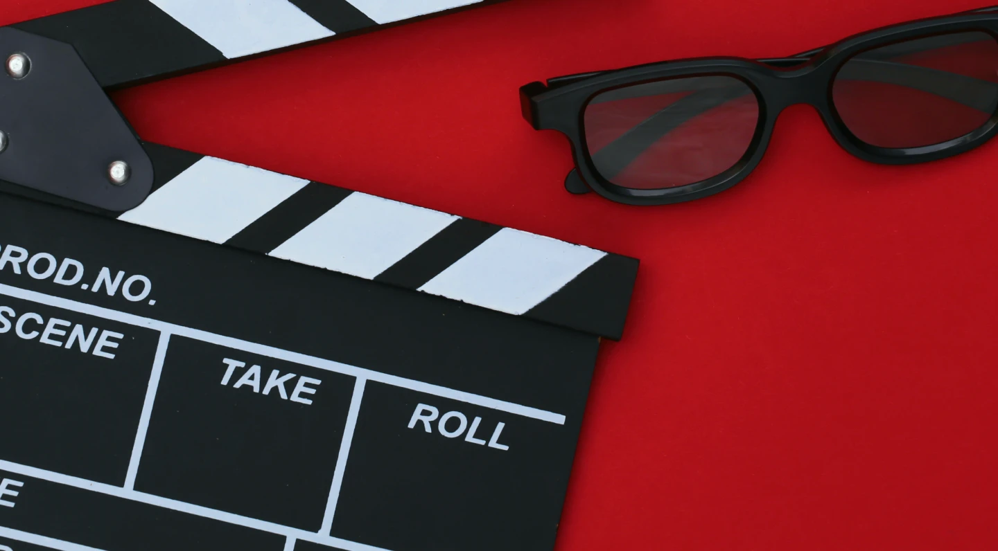 Retro VHS tapes and a photo on a red surface under pink lighting.