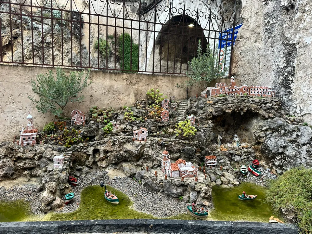 A detailed miniature village scene built into a rock grotto at Monastero Santa Rosa.