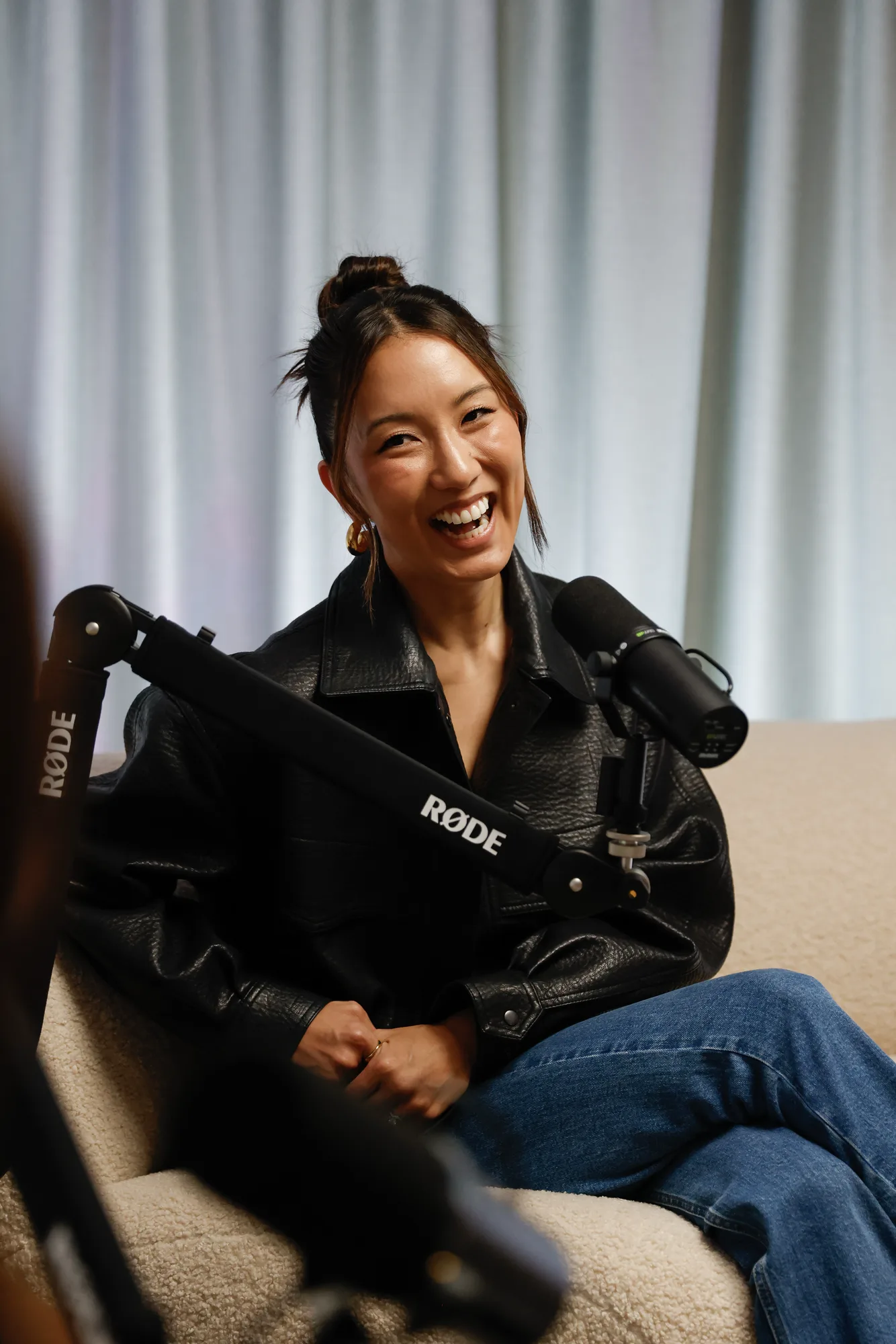A podcast creator laughing at the microphone during a recording