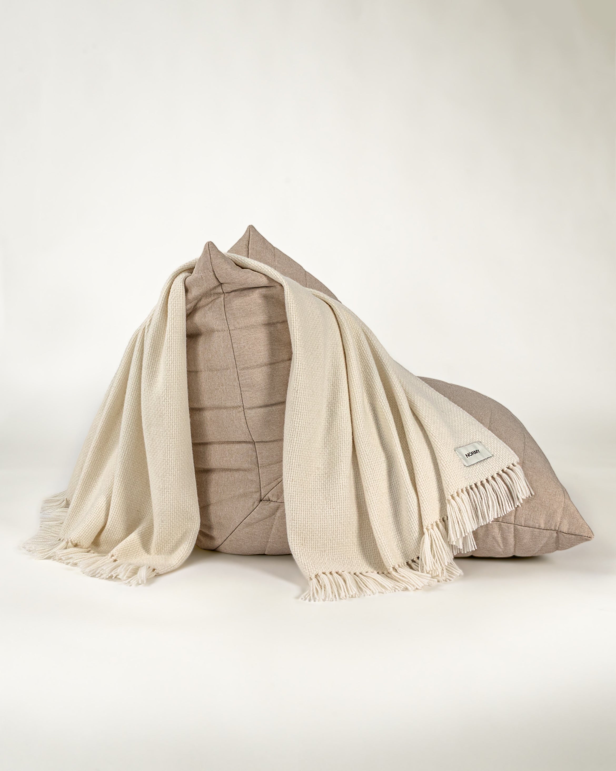 Normy Alpaca Blanket in moon draped over a chair, set against a clean off-white background.
