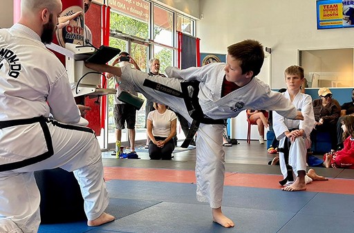 Student breaking a training board with a kick.