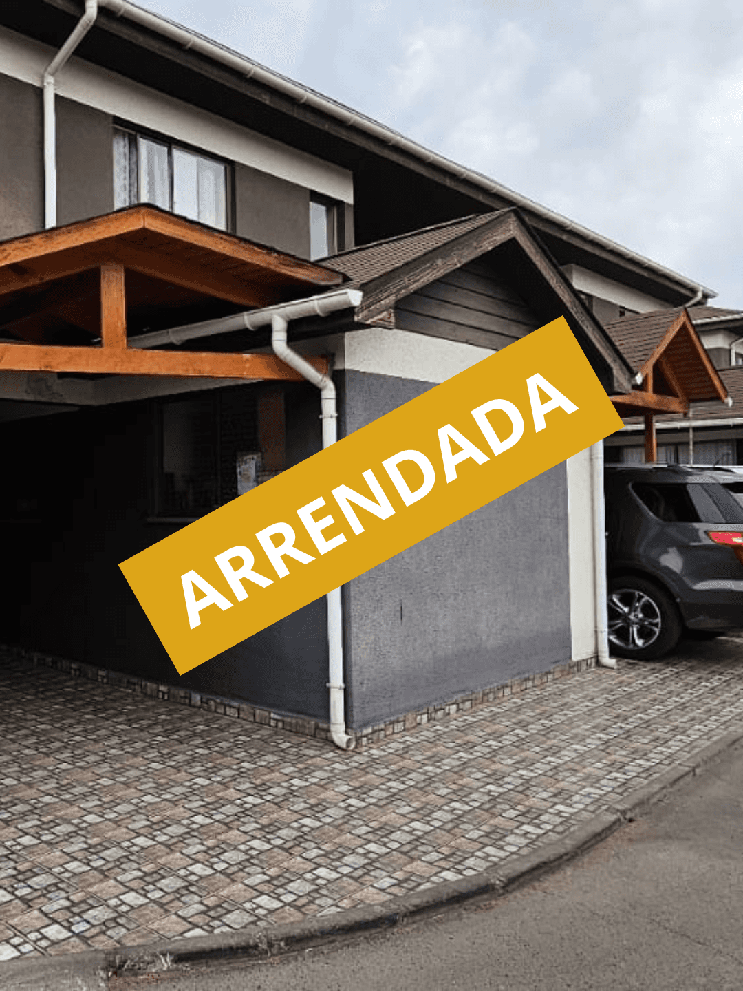 Large house with a wrap-around balcony overlooking a lit pool and deck at night.