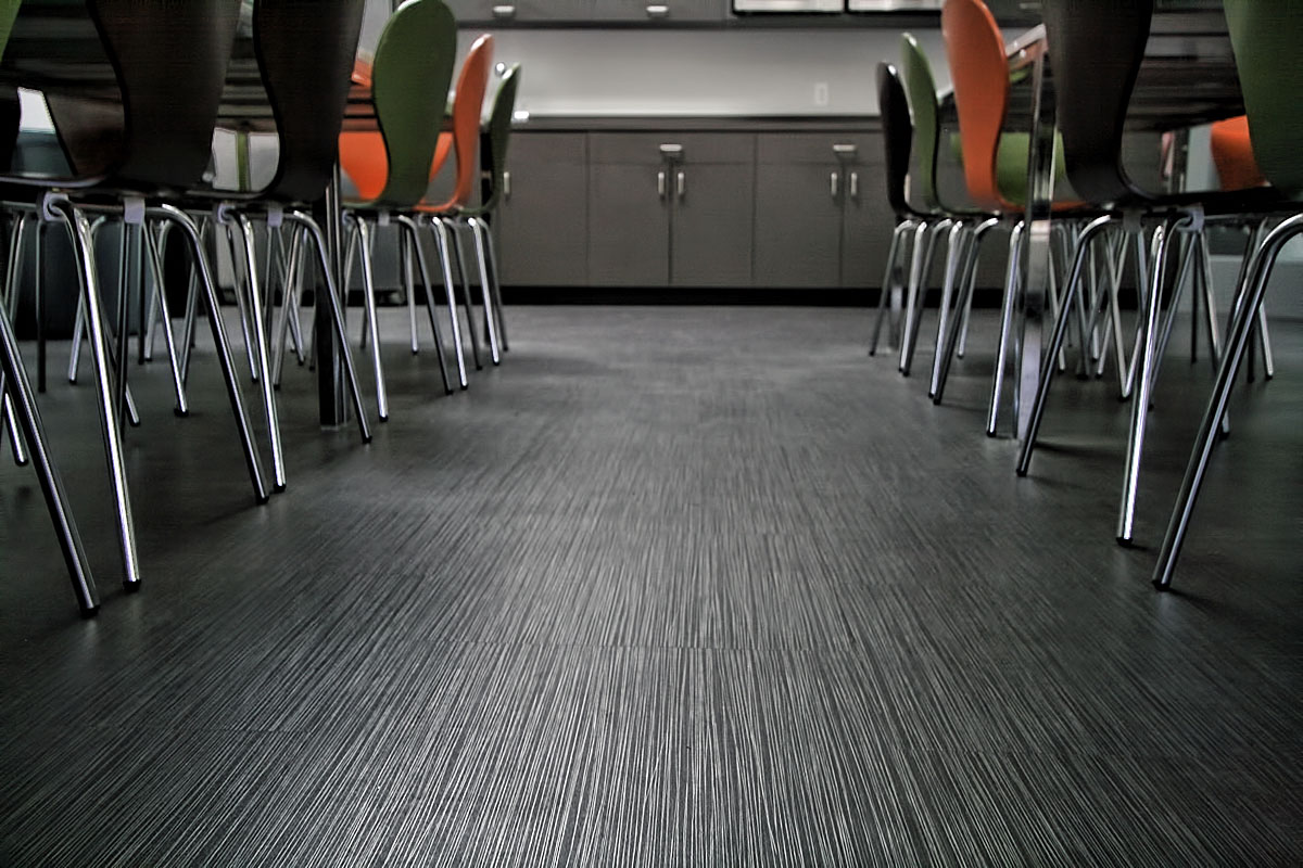 Close-up of the wood grain floor and chairs in the break room, highlighting the natural texture and simple elegance of the materials.