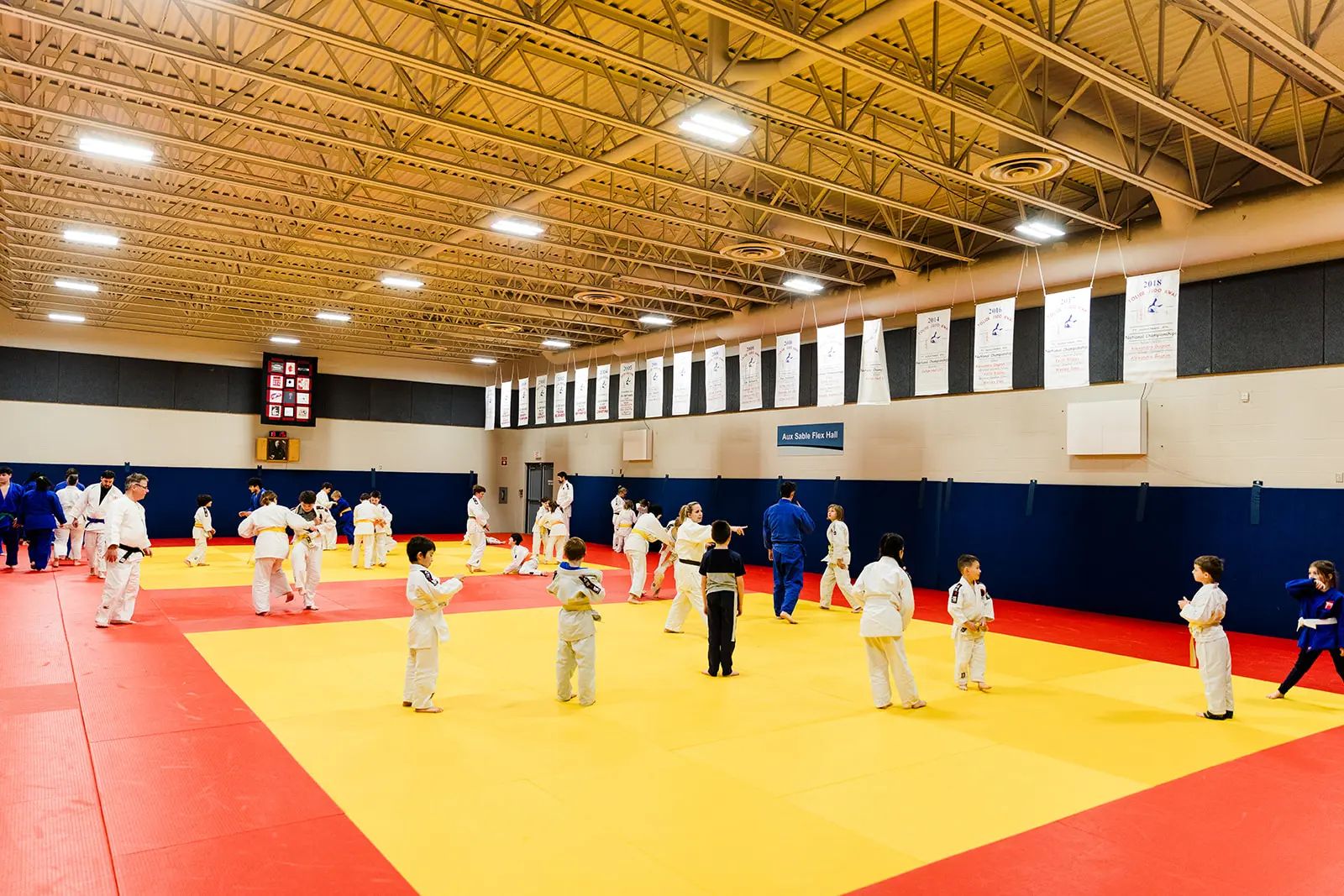 Wide camera shot of dojo during class with kids and adults