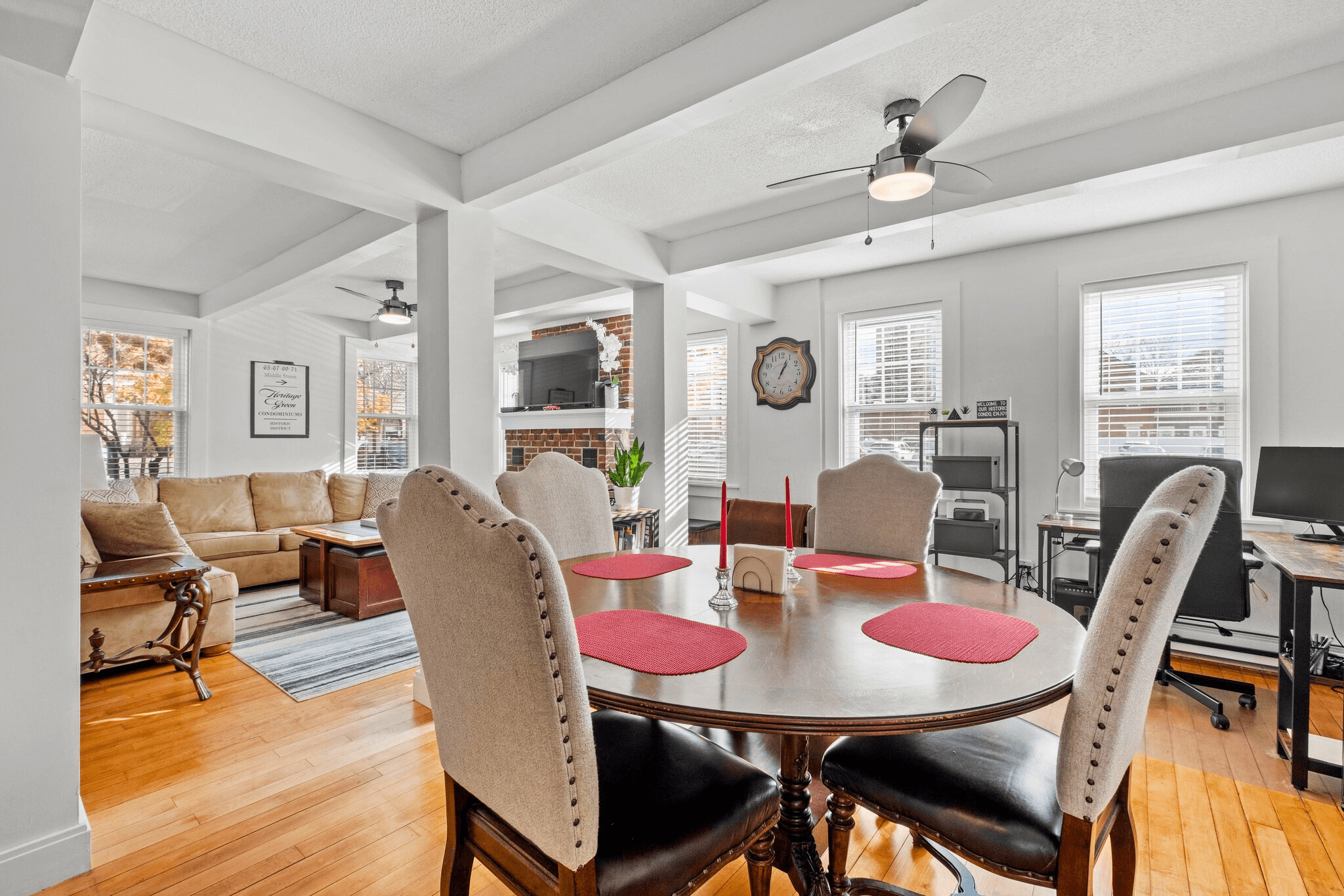 Lodgism-managed dining space in a Manchester, NH vacation rental, featuring a red round table, upholstered chairs, and natural light from large windows.