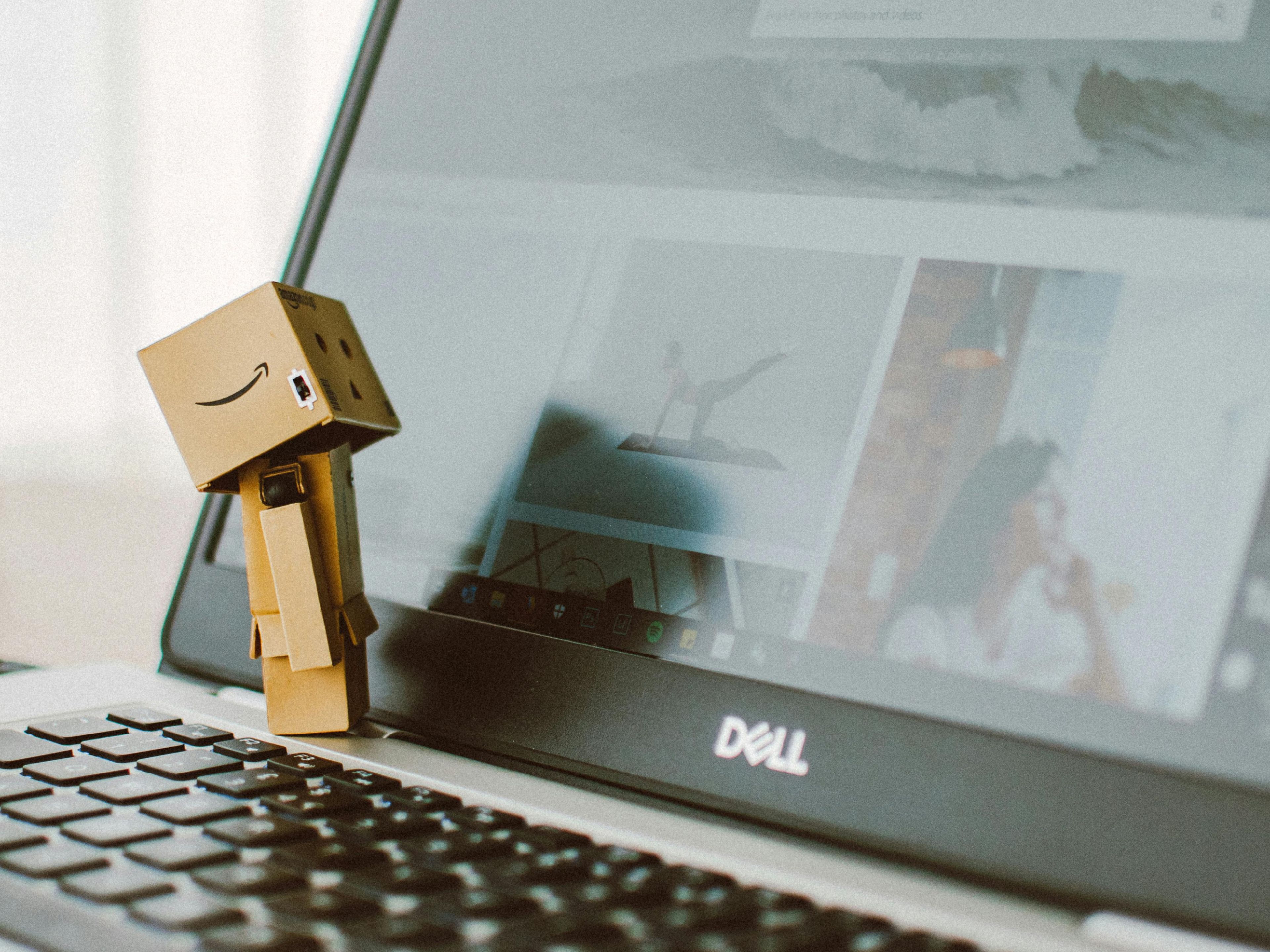 Photo of a laptop computer with a toy figurine standing on the keyboard, looking at the screen