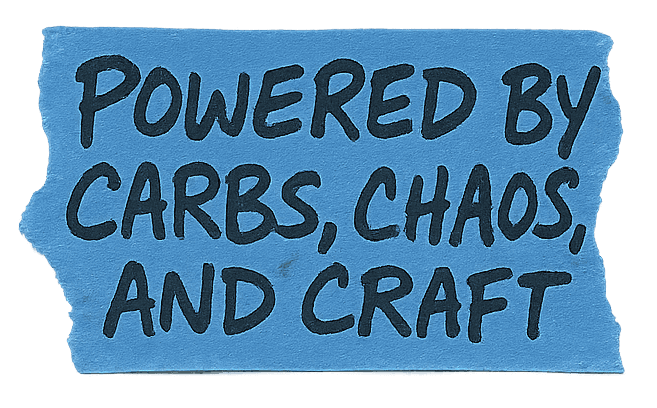 Text on a blue tape reads: "Powered by carbs, chaos, and craft."