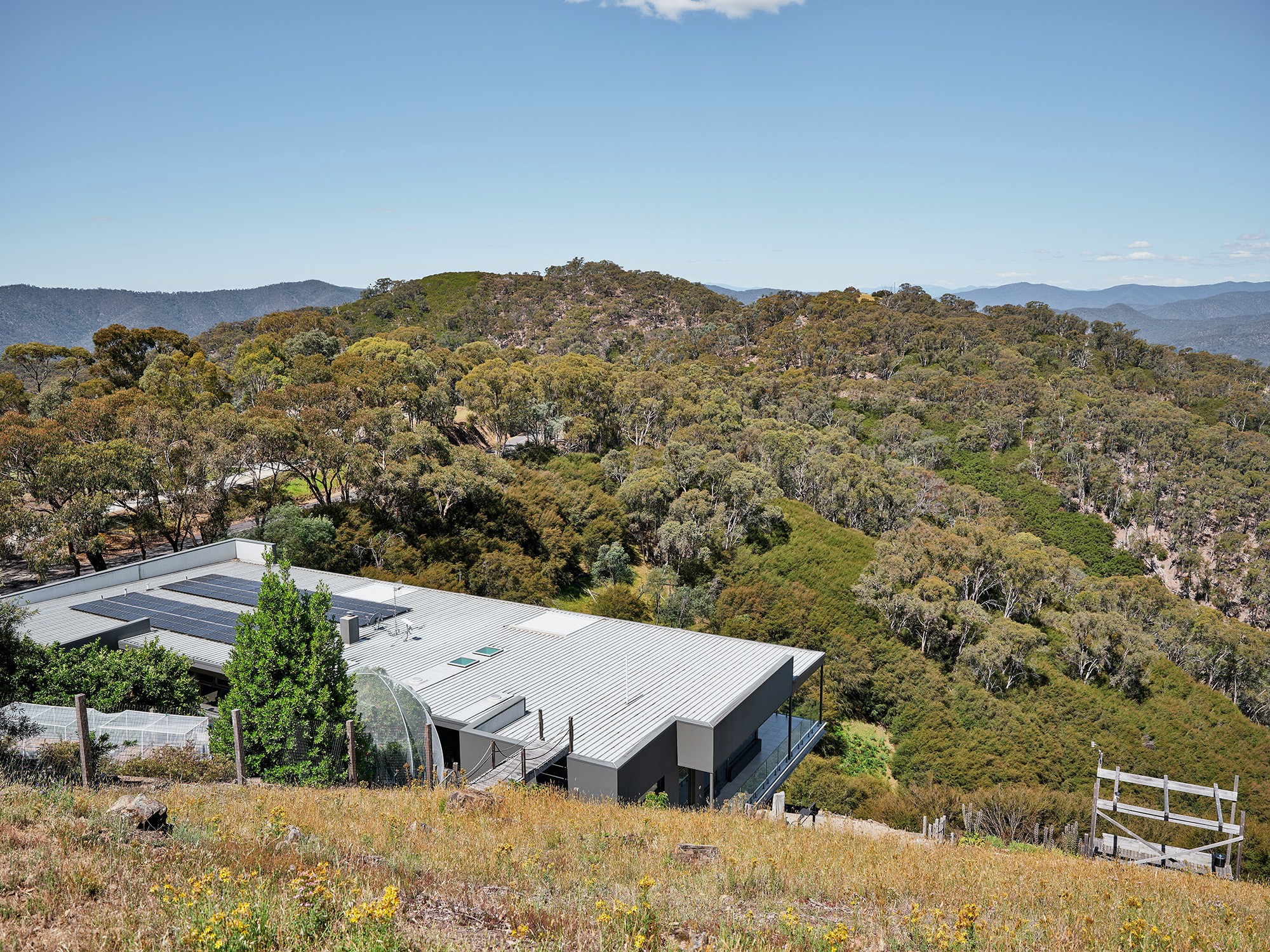 House with solar panels surrounded by forested hills
