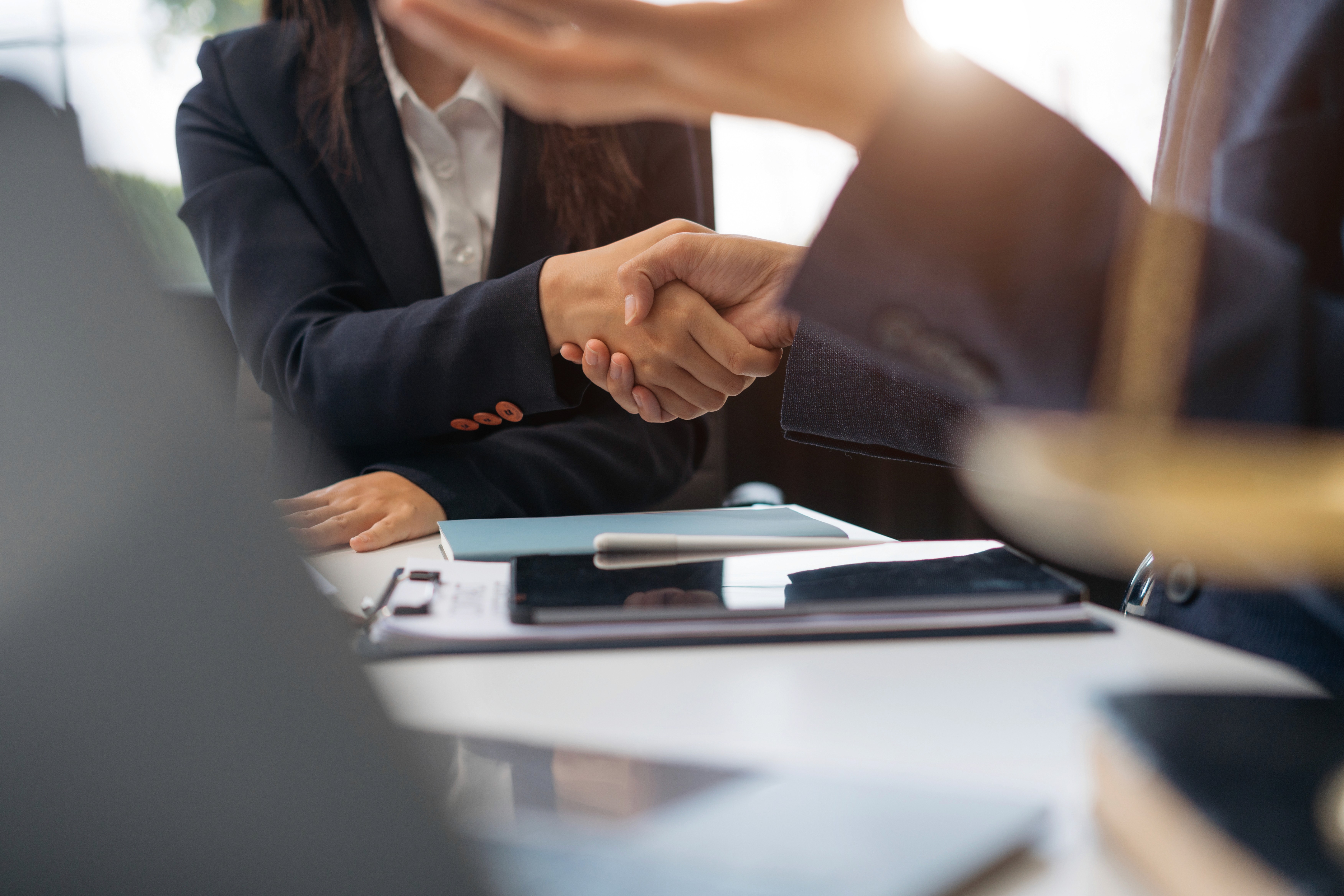Image of a client shaking hands with a lawyer across a clean, minimalist conference table.