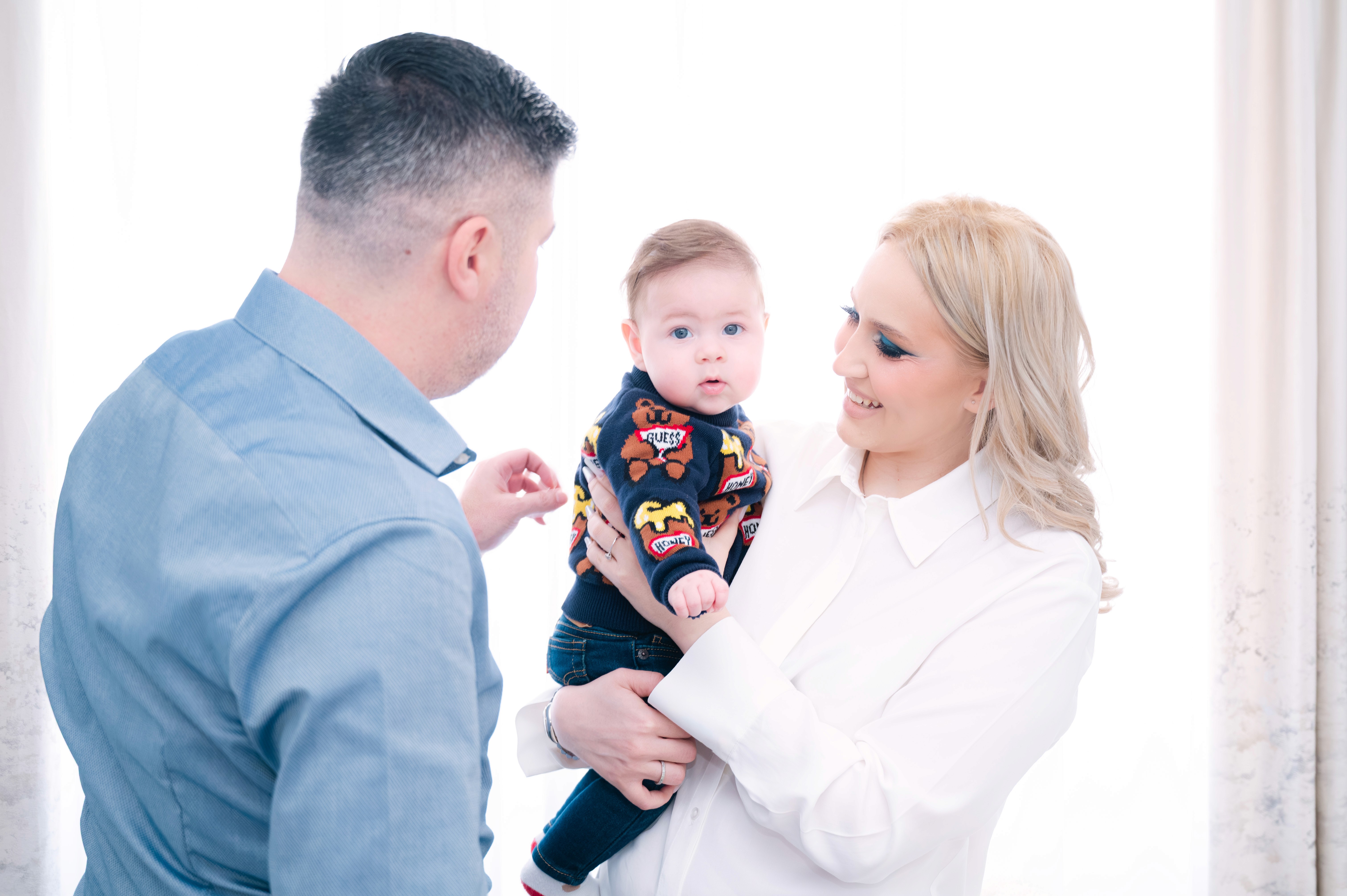 Tatăl și mama privind copilul înainte de ceremonie, moment intim surprins natural.