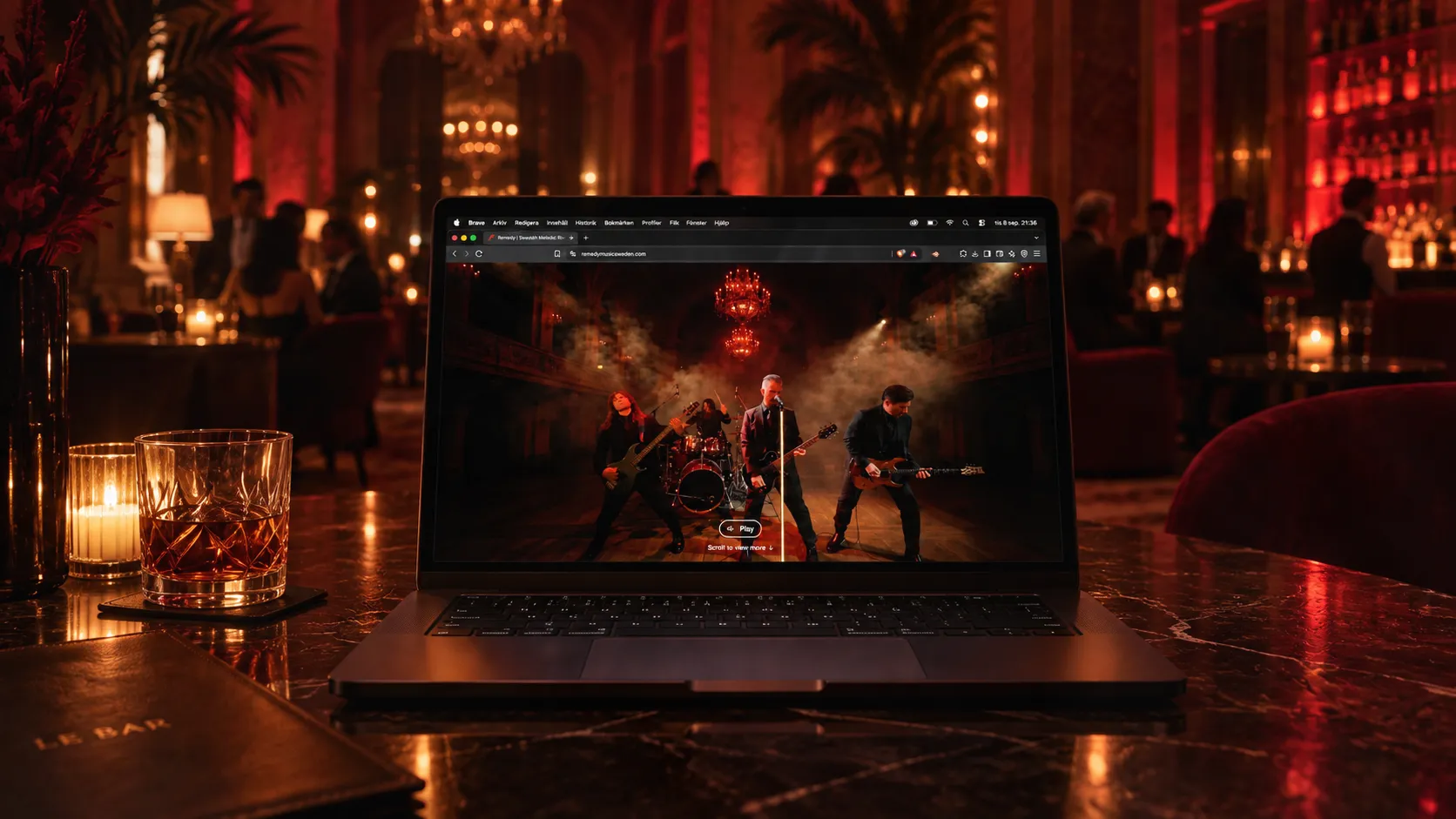 Laptop displaying the Remedy website on a marble table in a red-lit luxury hotel lounge with blurred guests in the background.