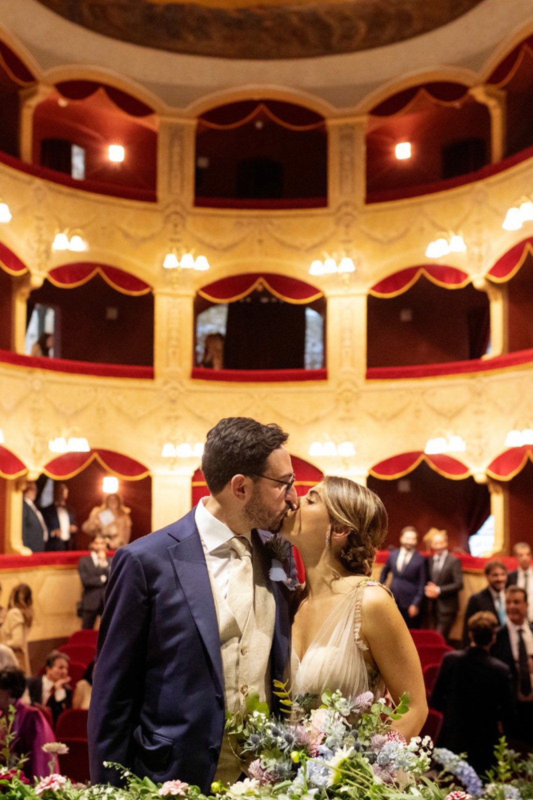 A bride in a lace wedding dress gently holds.