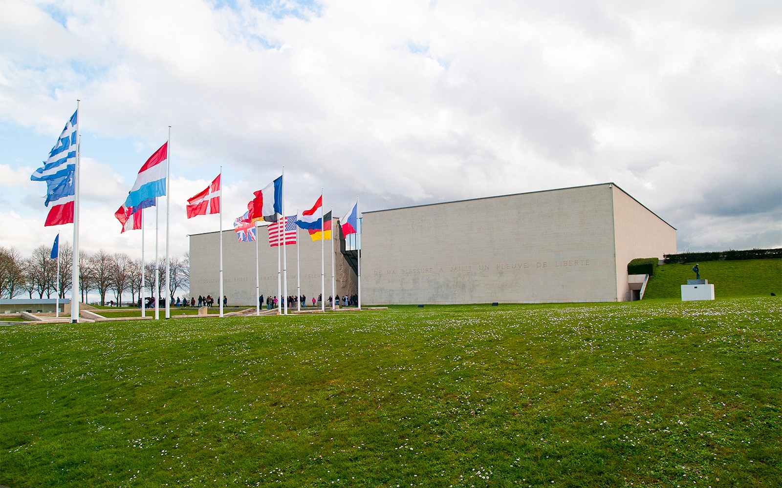 Flags outside the Caen Memorial Museum in France, with visitors entering.