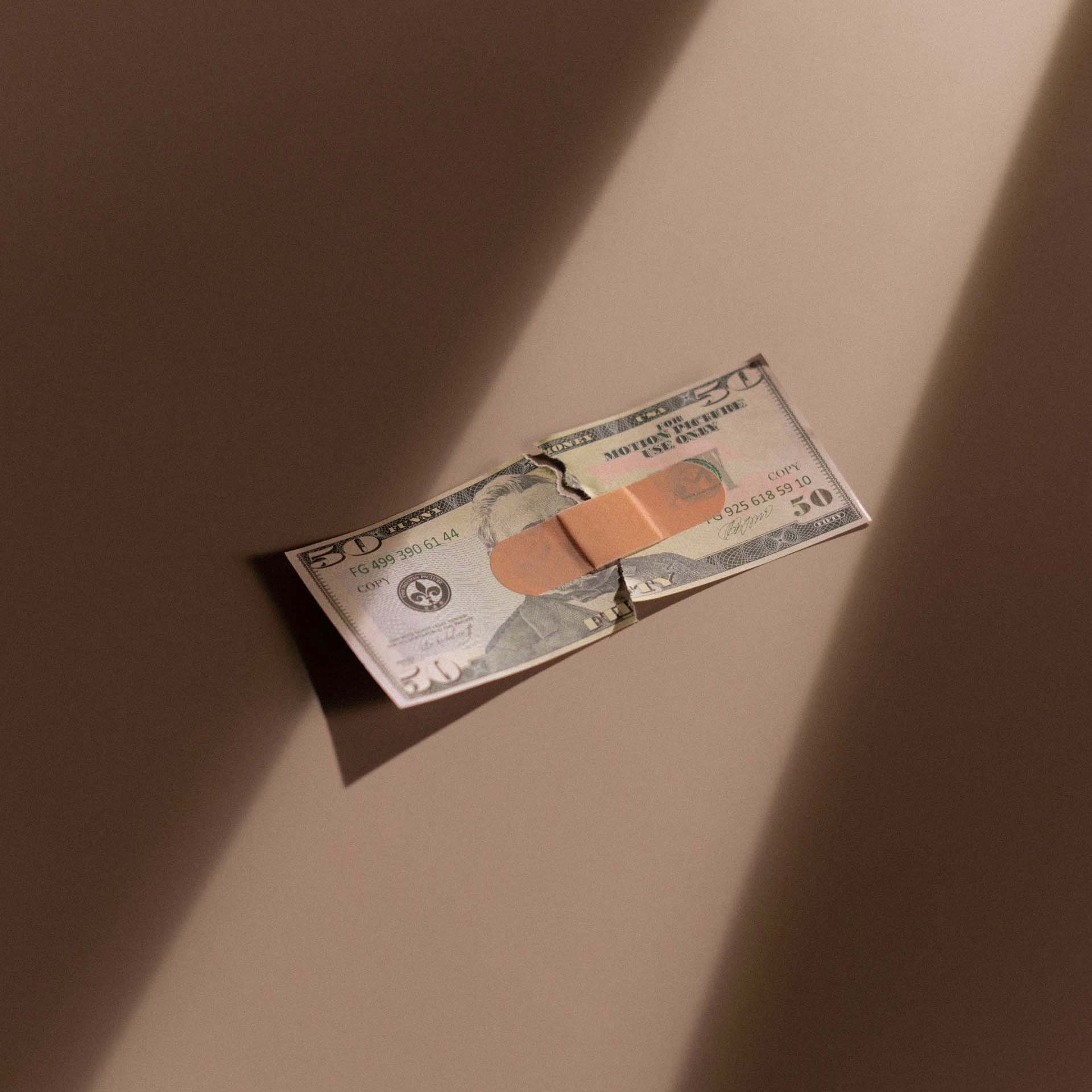 Torn fifty dollar bill repaired with bandage