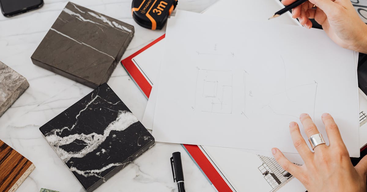 Hands holding architectural sketches with marble samples and measuring tape on a desk.
