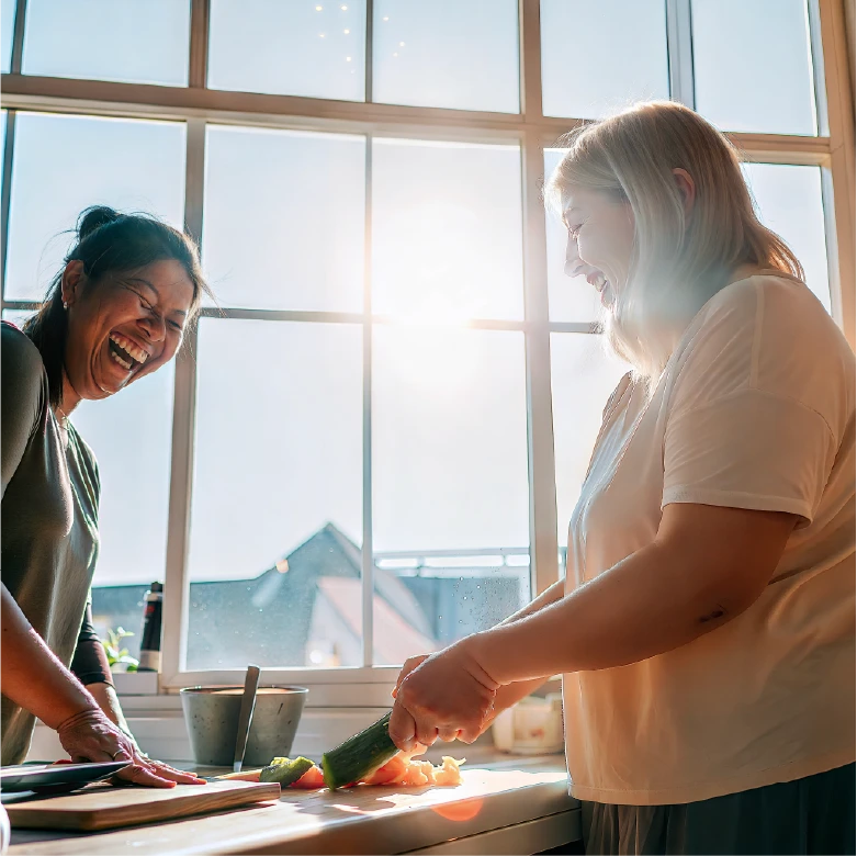 two women laughing and cutting vegatables