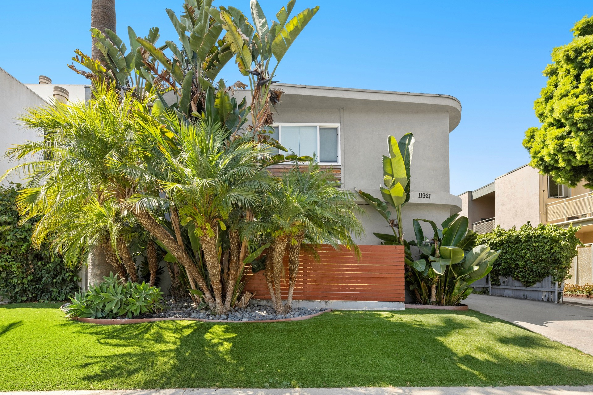 Landscaped front yard with tropical greenery and clean exterior design at 11921 Goshen Ave property.