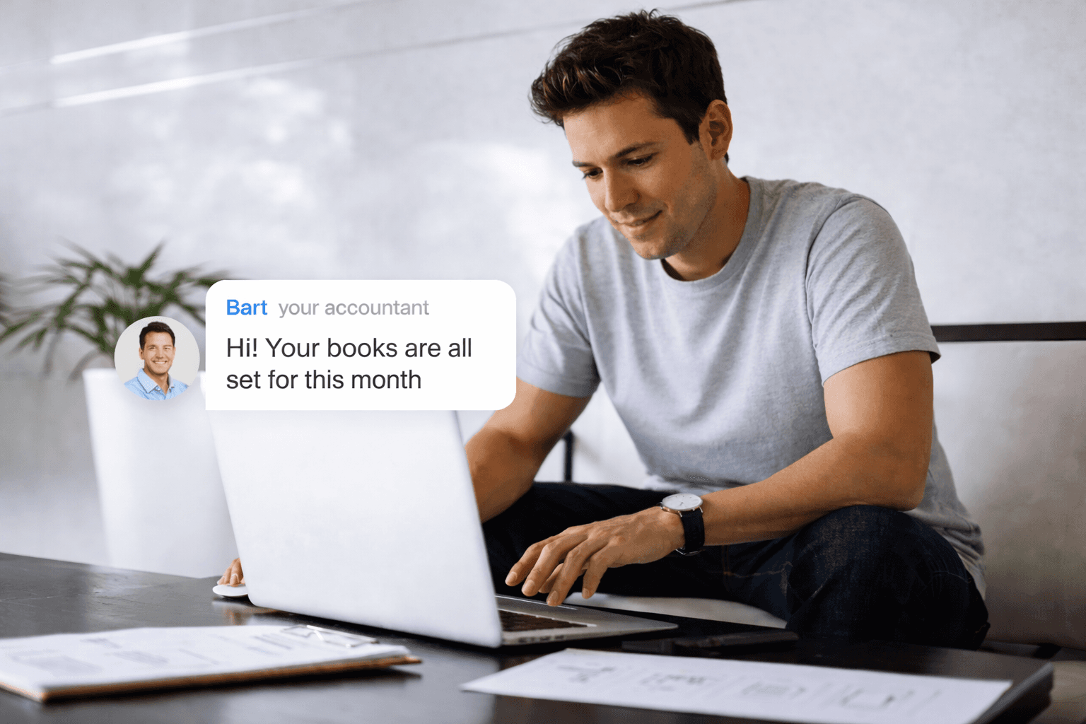 man in white dress shirt sitting in his office which has a pink background wall