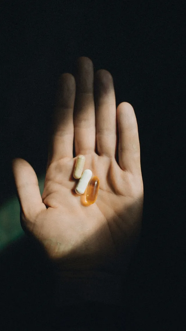 Hand holding L-Citrulline capsules and a softgel