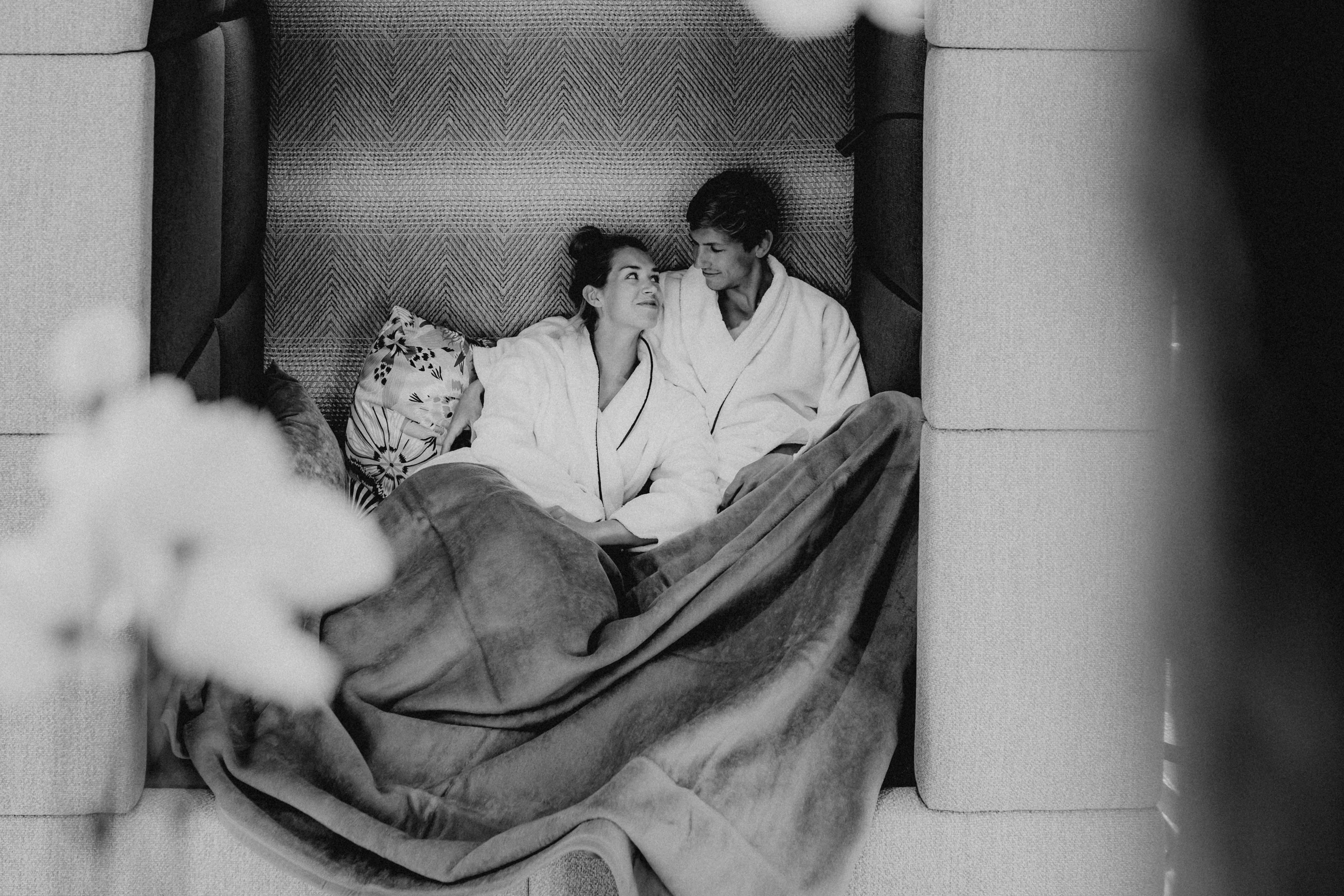 A modern lounge area with elegant furniture, soft lighting, and a decorative tree centerpiece. Monochrome setting.