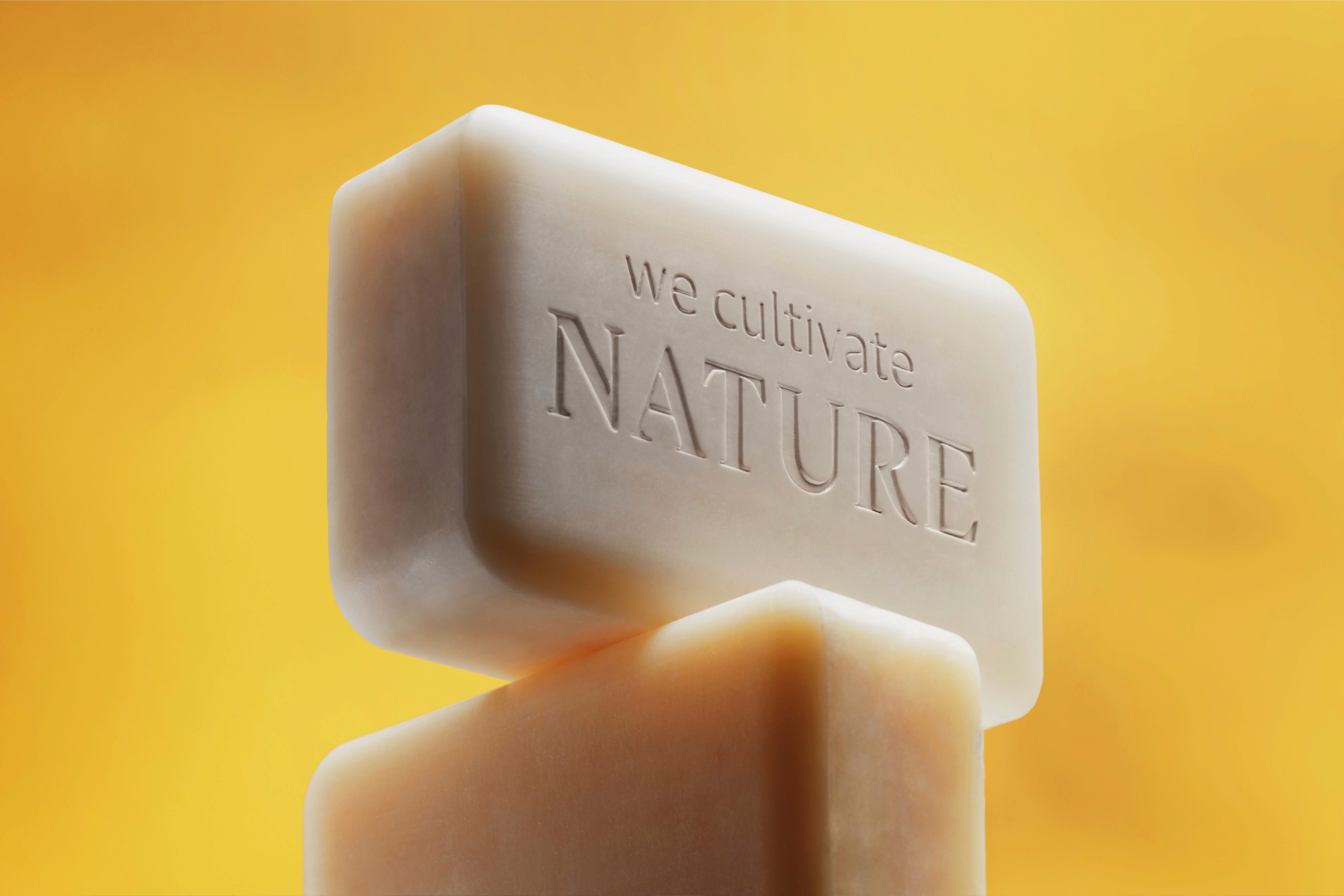 A close-up of a bar of soap with a smooth texture against a warm yellow background.