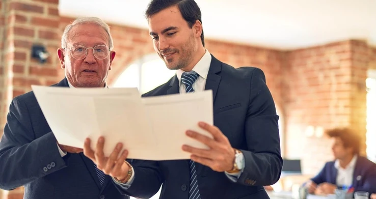 Dois homens de terno lendo um documento juntos