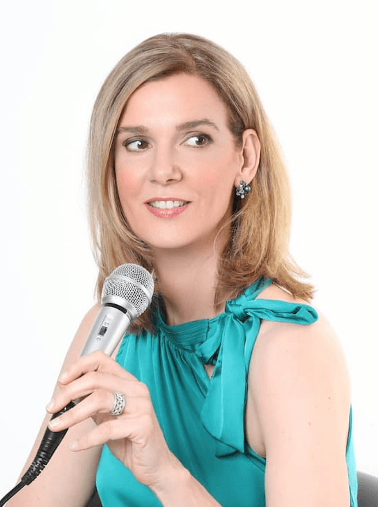 Vocal Coach Danielle Zuber im professionellen Auftritt. Nahaufnahme mit Mikrofon und türkisfarbenem Oberteil, strahlendes Lächeln.