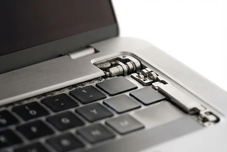 Macro detail of a MacBook Pro hinge and keyboard, representing precision craftsmanship.