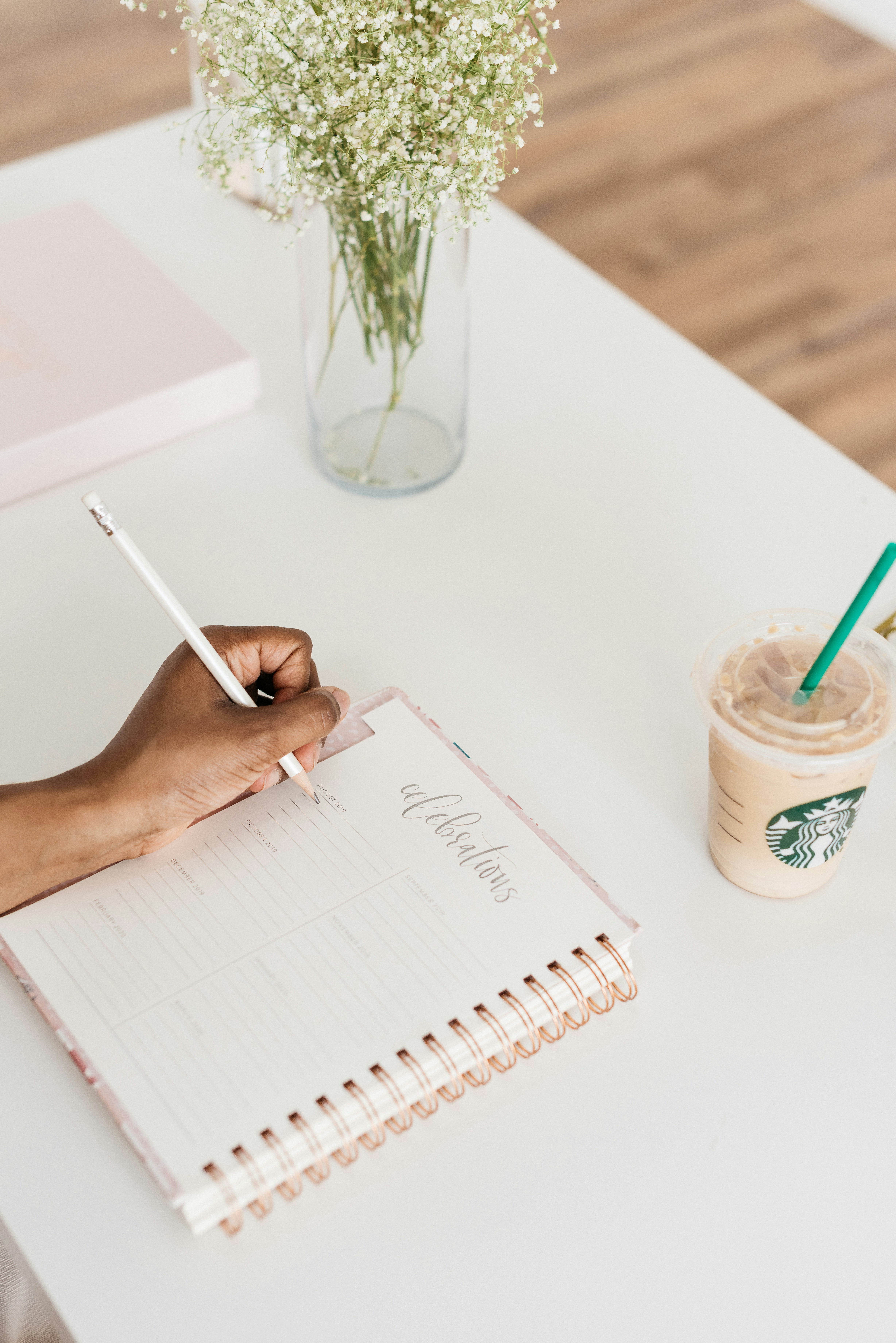Person writing structured notes in a notebook at a bright clean desk