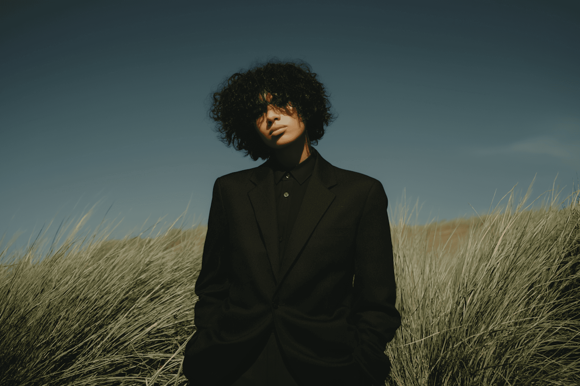 Person standing in a field wearing a black outfit with natural background