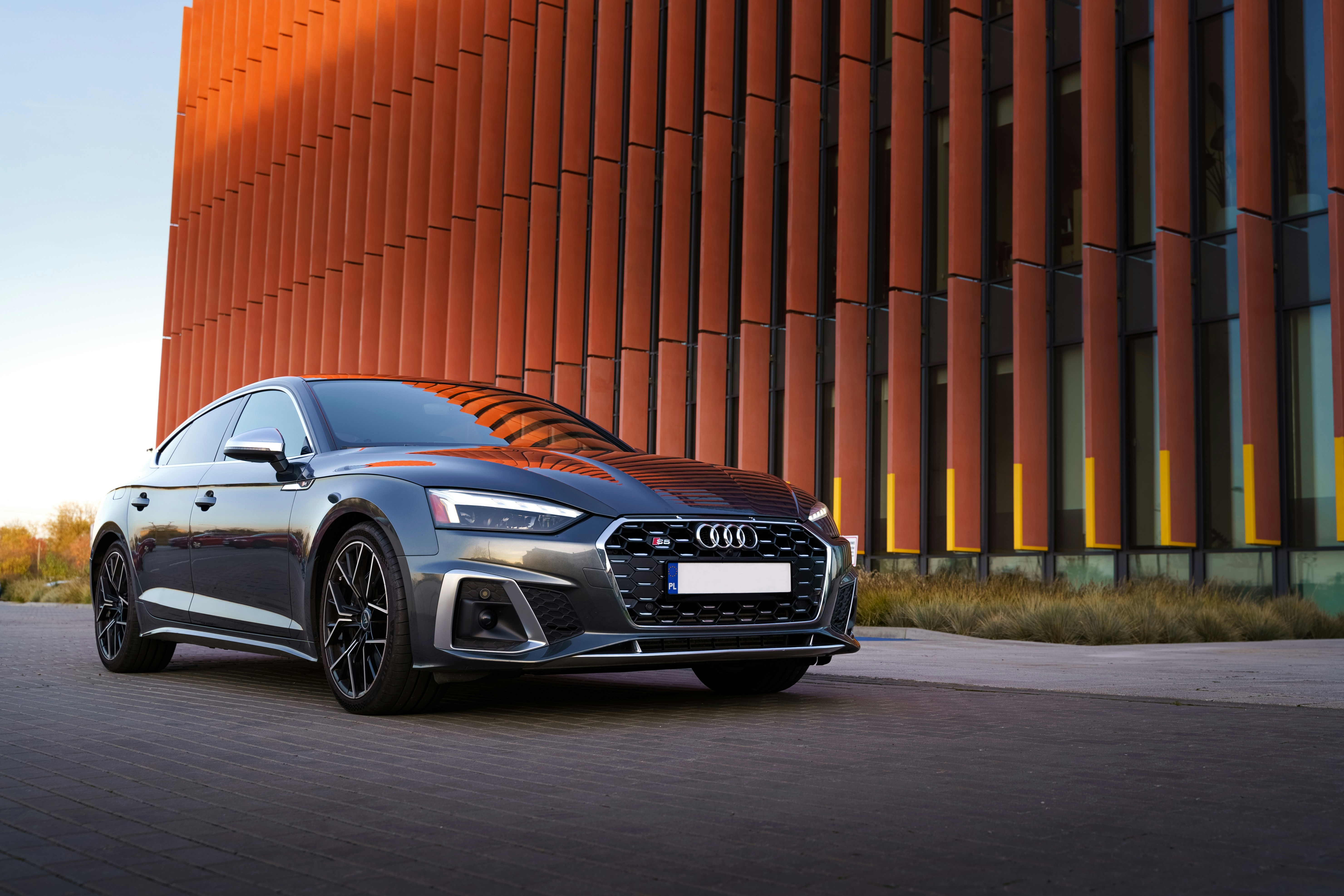 An audi sits in front of a tall building.
