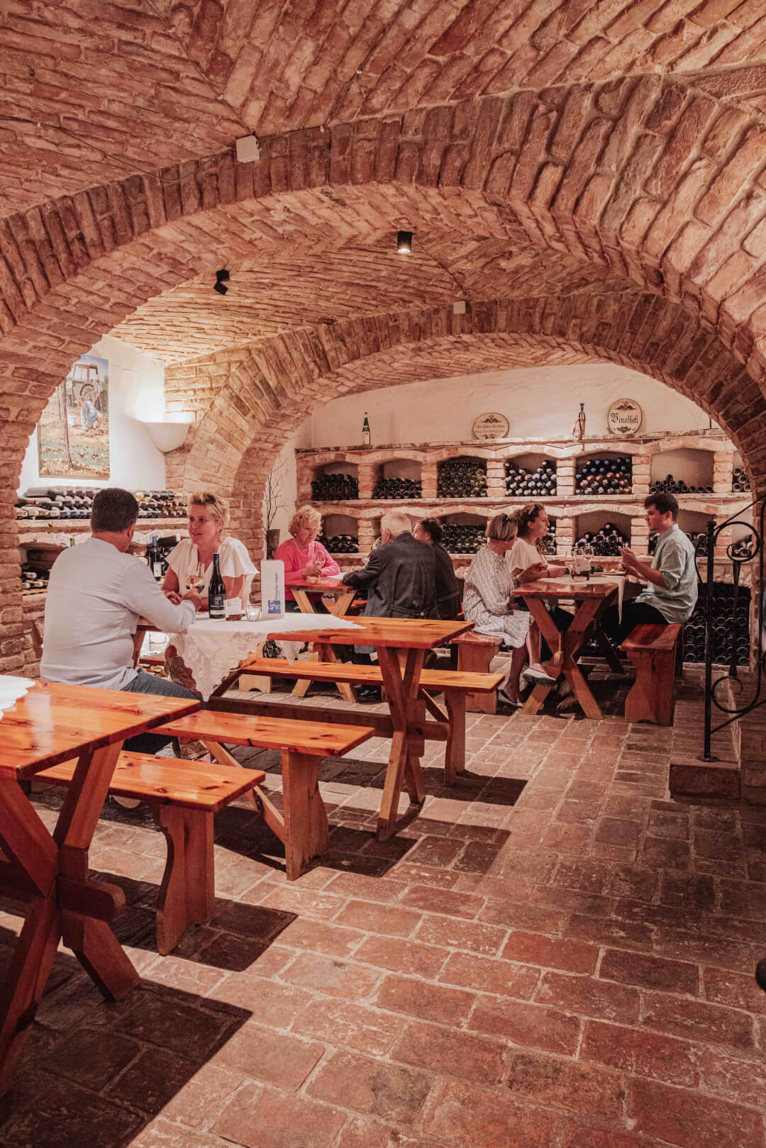 Professionelle Gastronomie- & Interieur-Fotografie: Gemütliche Lounge-Ecke mit rotem Sessel und beleuchteter Wein-Präsentation, inszeniert mit warmem Ambient-Licht und Fokus auf Design-Details.