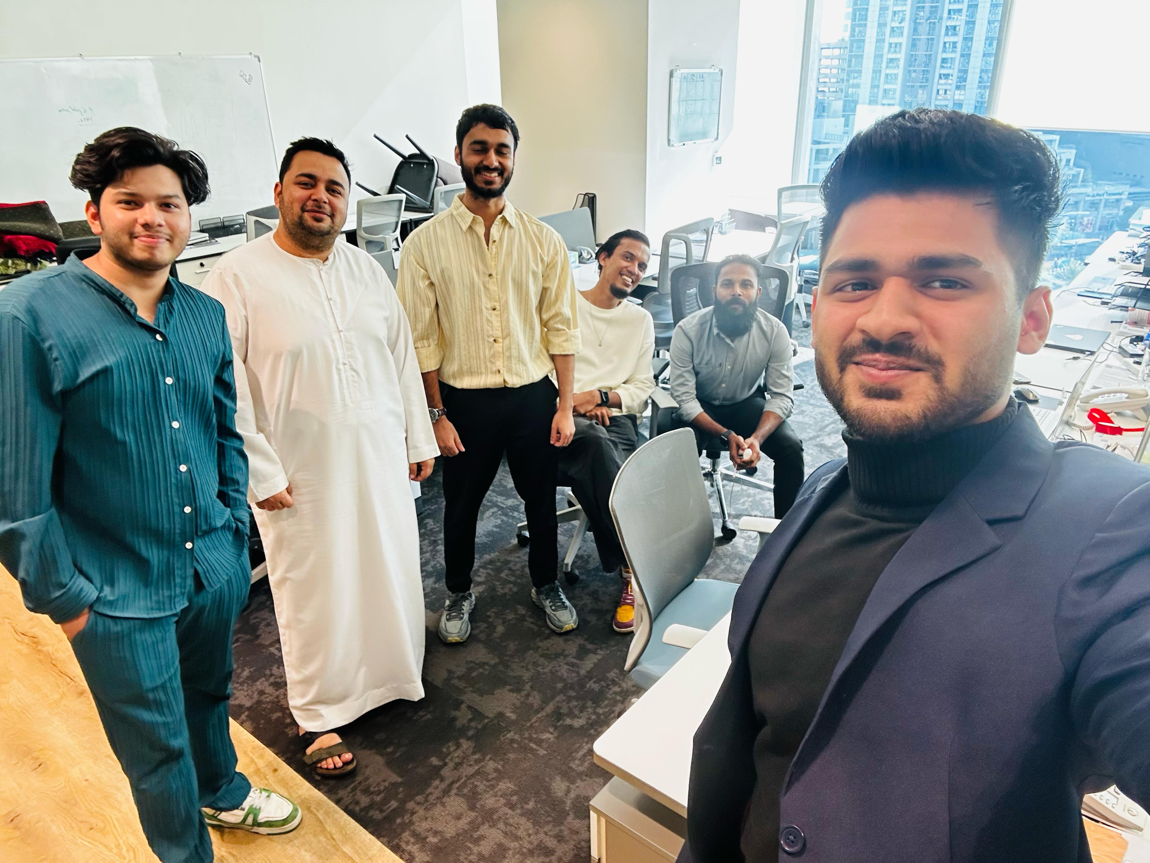 Four diverse professionals collaboratively working on a laptop, with one person pointing at the screen while others observe.