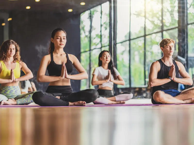 A yoga class meditating together in a bright studio
