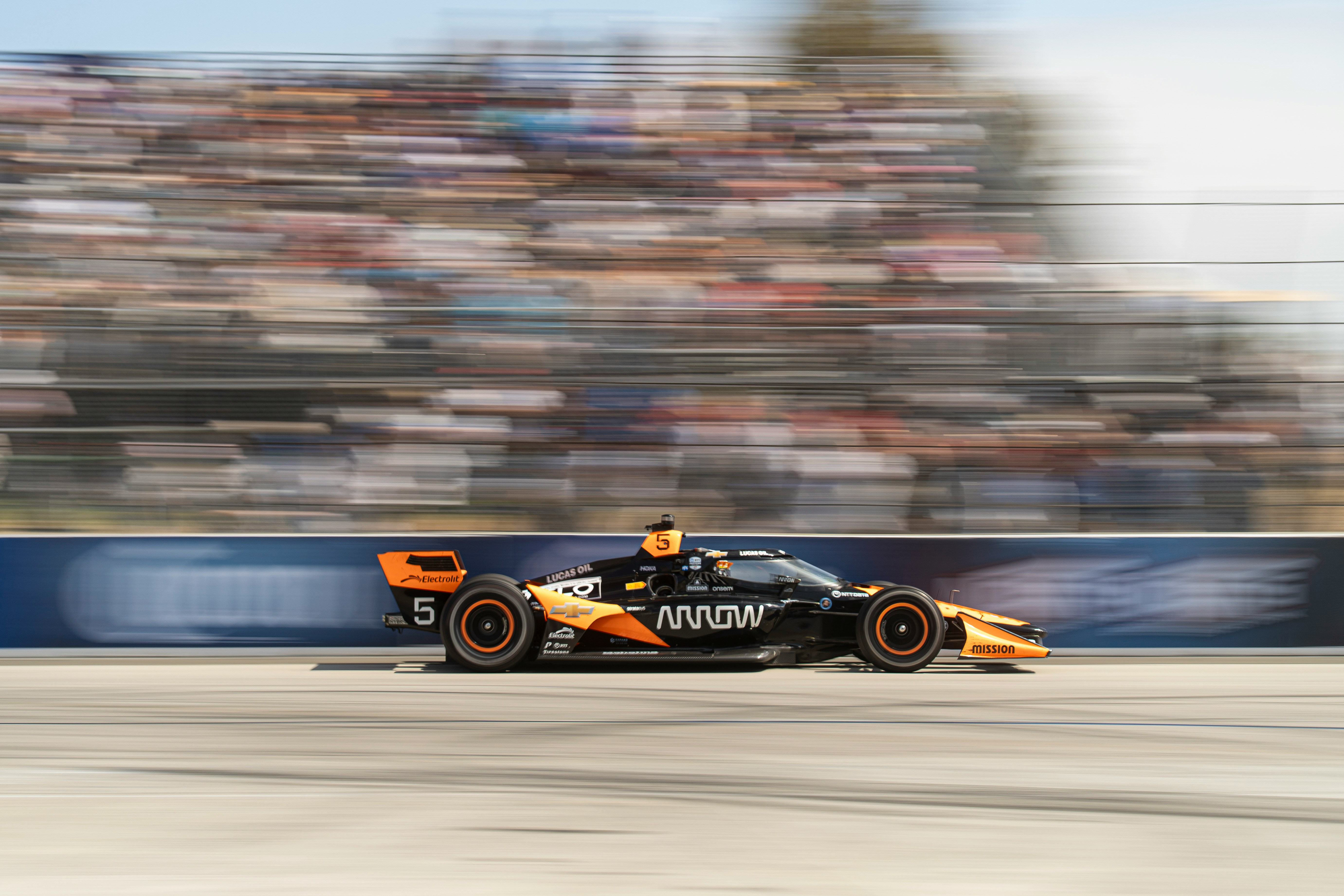 A race car speeds past the blurry crowd.